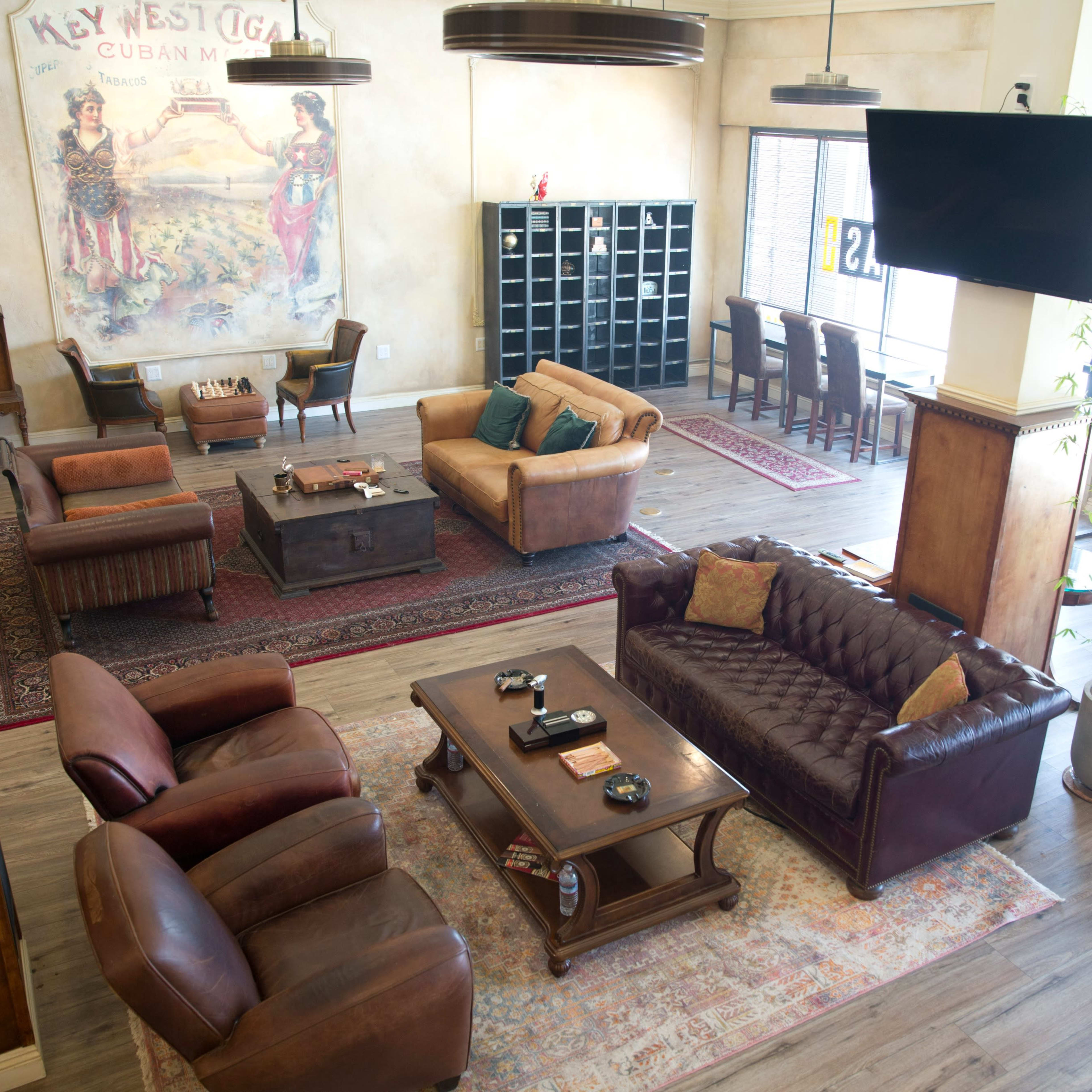 The interior of a spacious lounge features leather seating, a wooden coffee table, and a mural depicting a Cuban theme on the wall.
