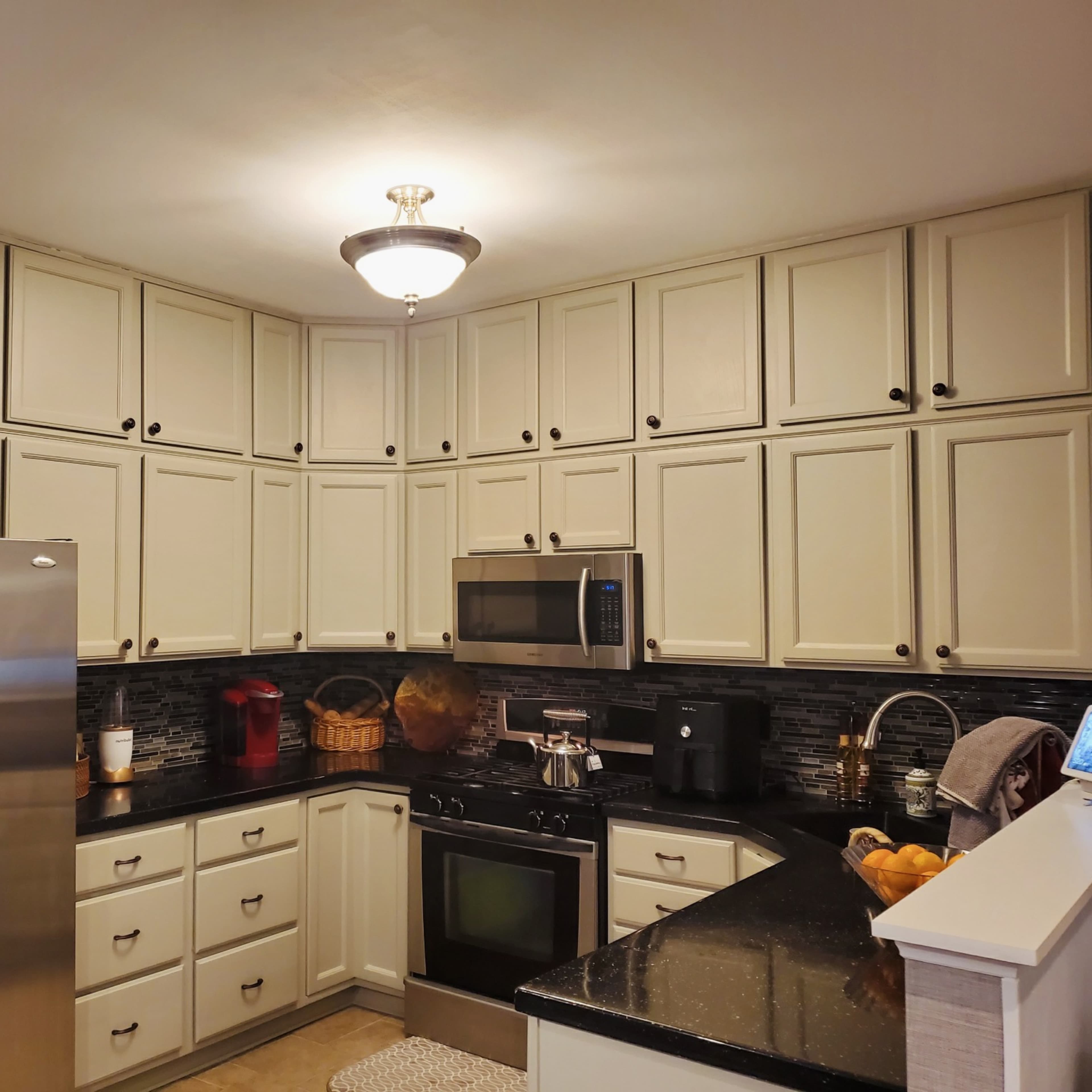 A modern kitchen with light cabinets, black countertops, and stainless steel appliances.