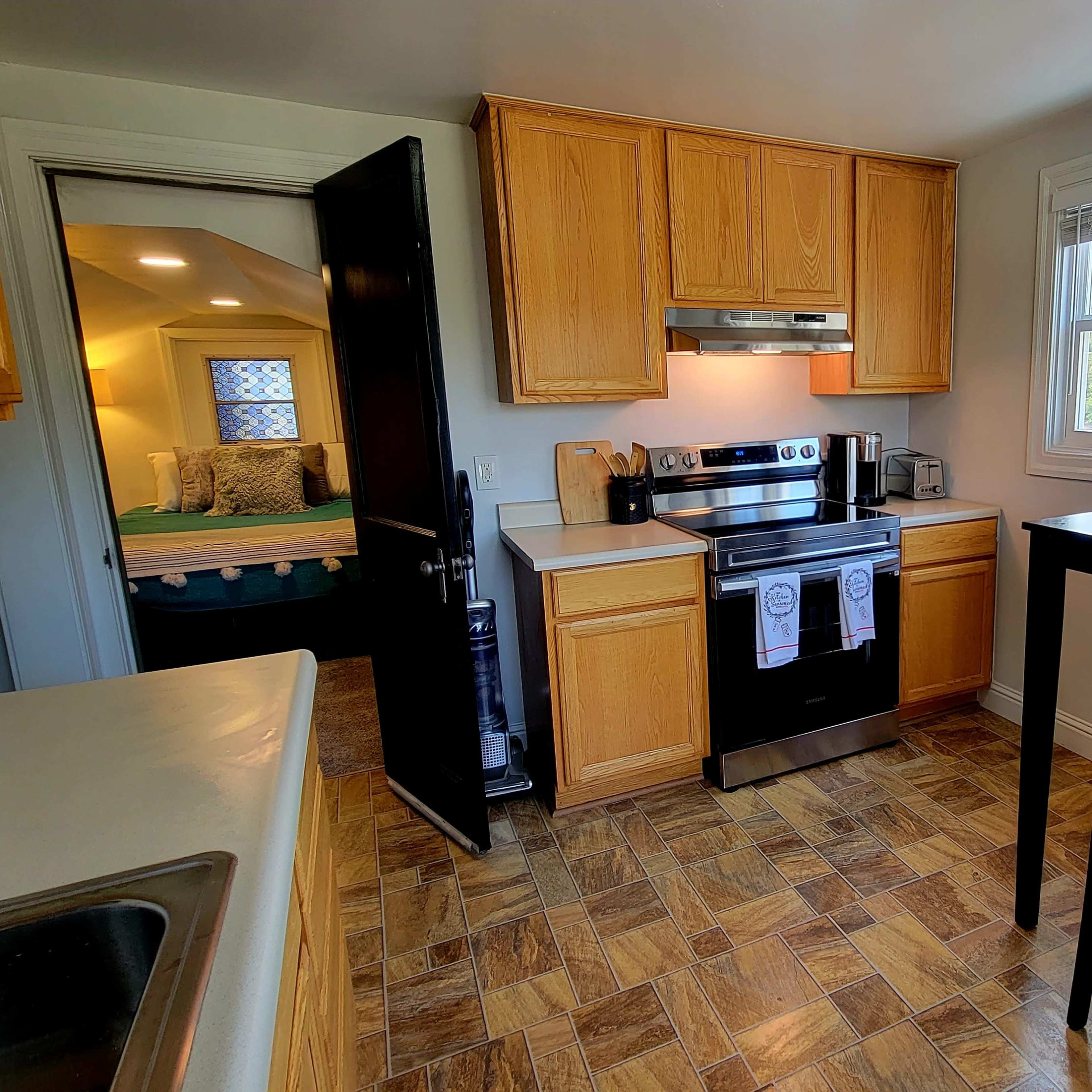 A modern kitchen with wooden cabinets, an oven, and a small dining table near the windows.