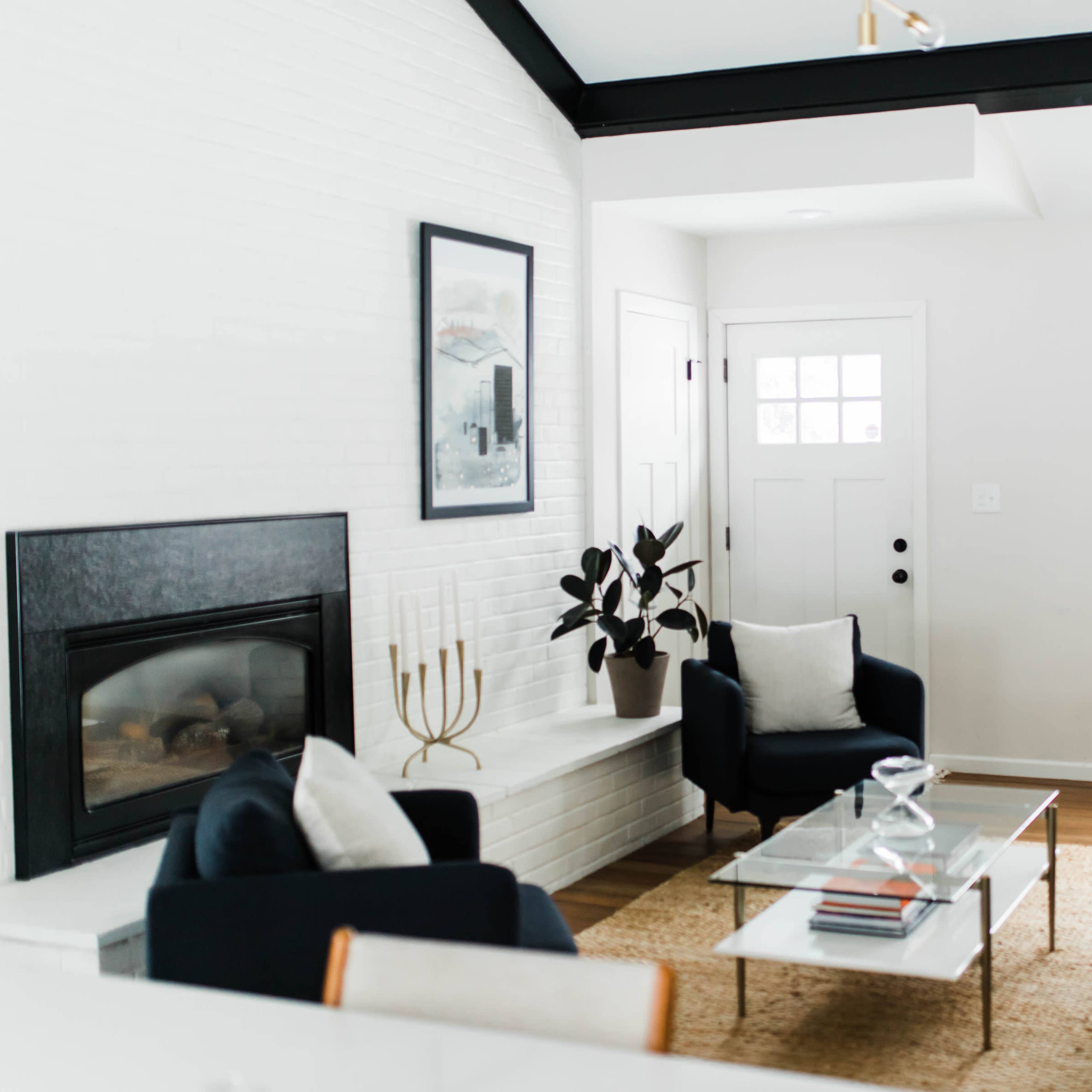 A modern living room with a fireplace, a coffee table, and a seating arrangement near large windows.
