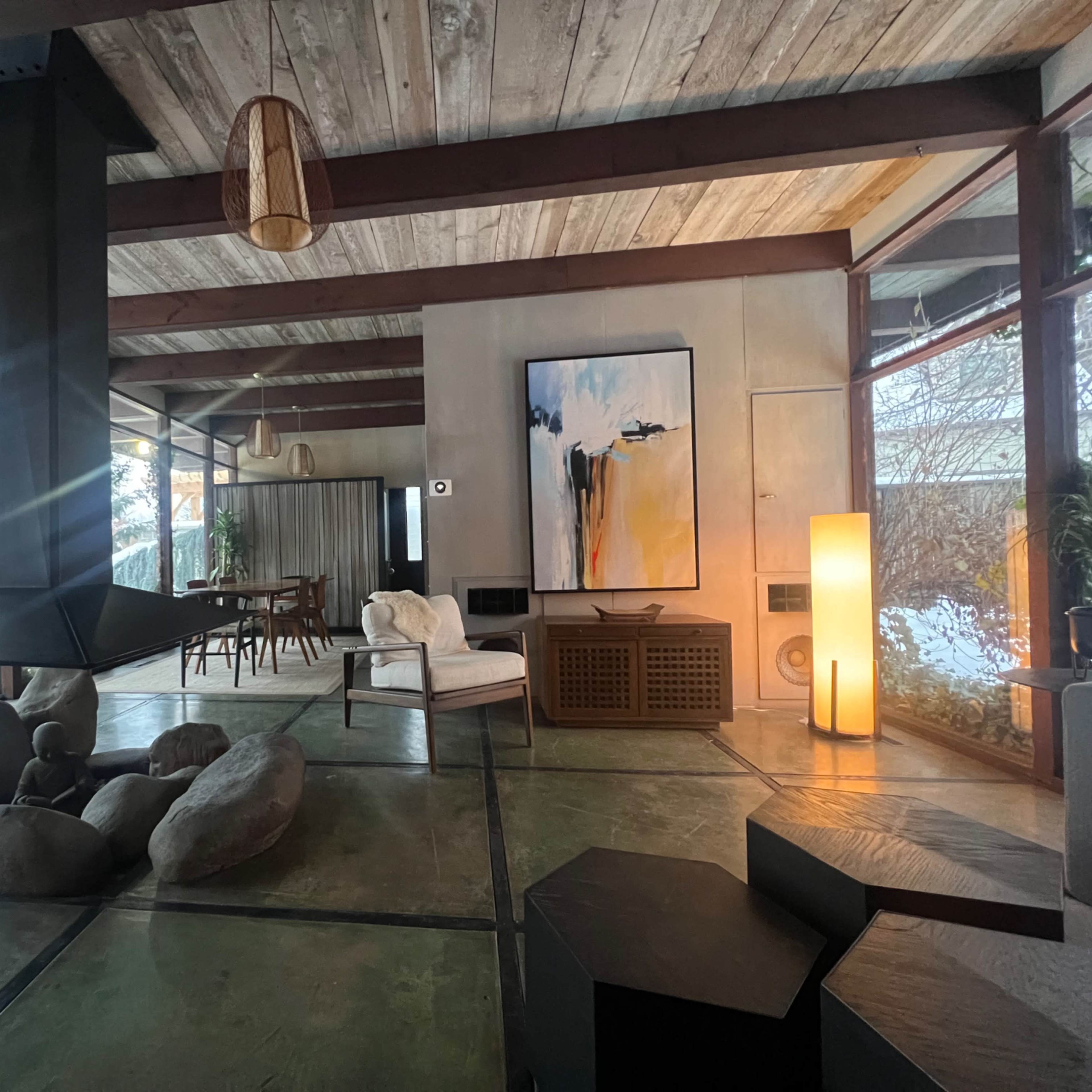A spacious living area features a central stone arrangement, a modern fireplace, and large windows providing a view of the snowy outdoors.