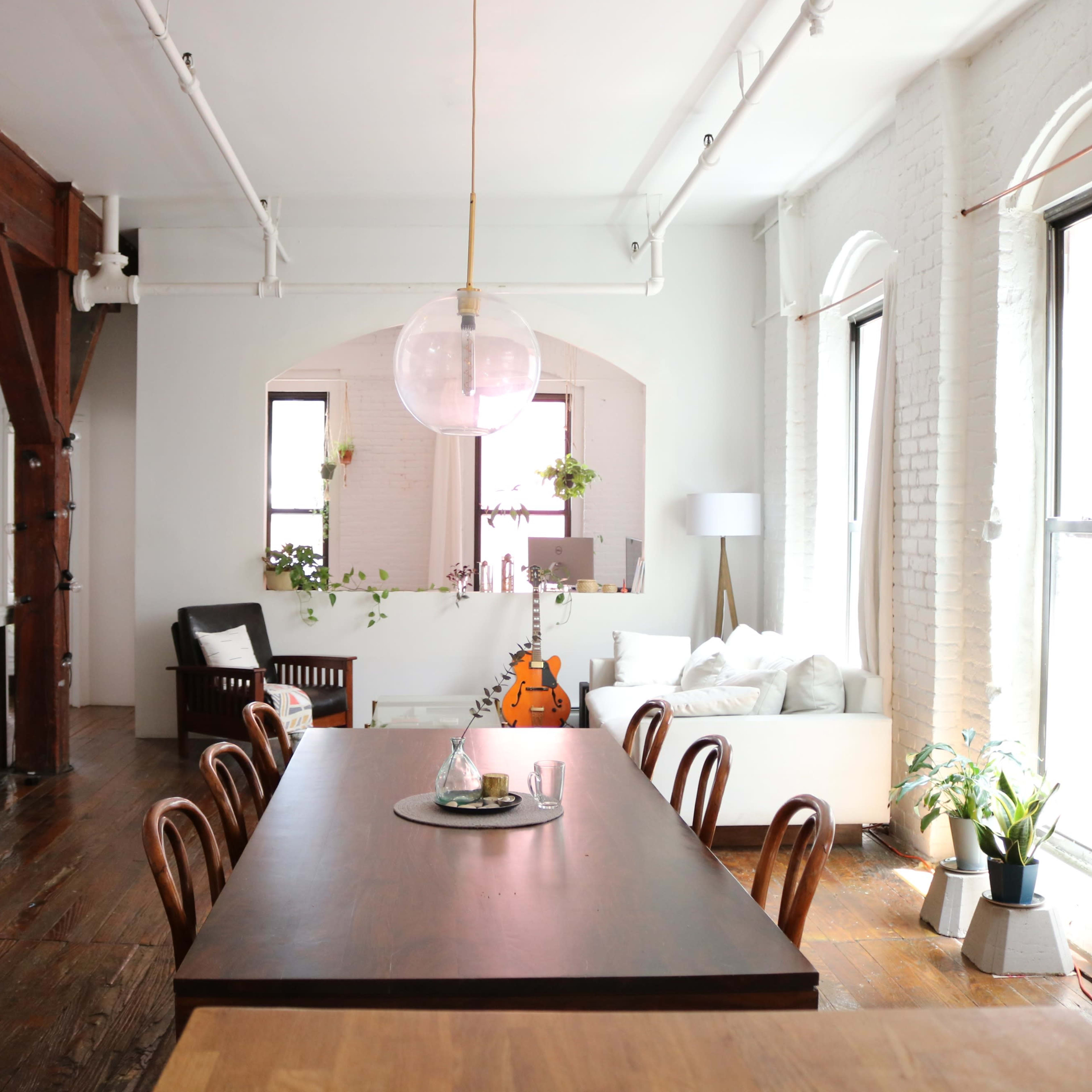 A spacious dining area features a large wooden table surrounded by chairs, with a cozy living room visible in the background.