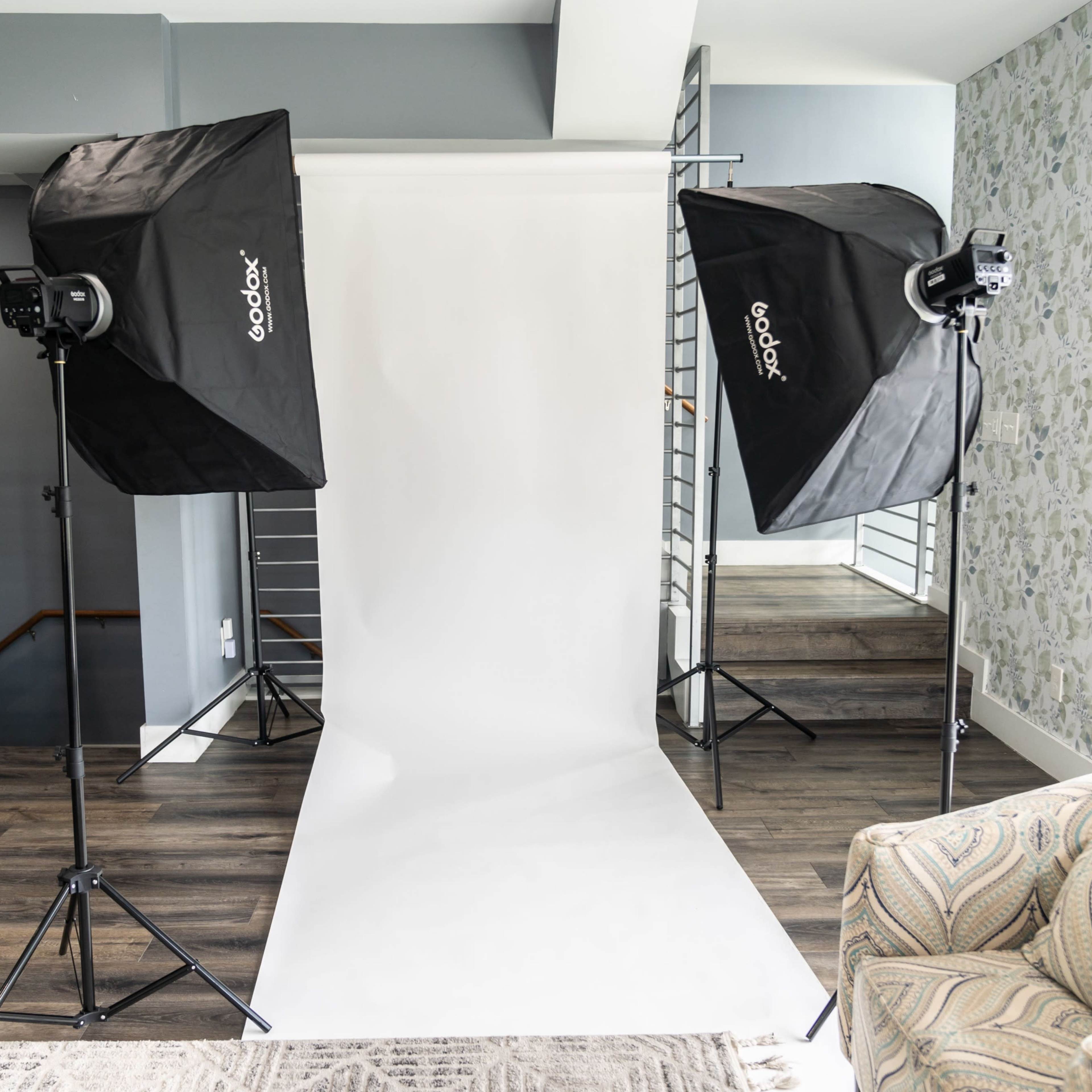 A photography setup with two softbox lights flanking a white backdrop in a well-lit room.