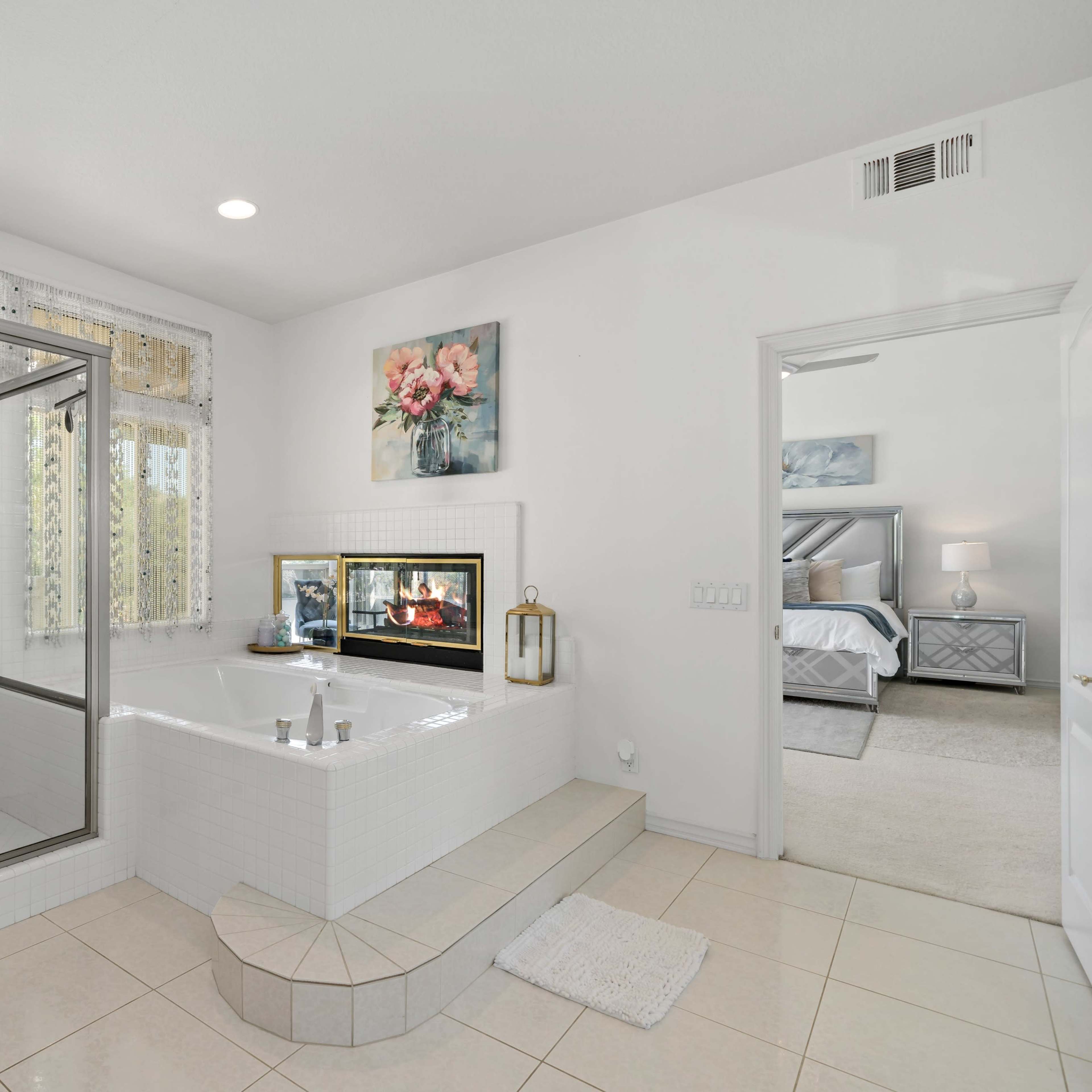 A modern bathroom featuring a glass-enclosed shower, a jetted bathtub with a tiled surround, and a window with sheer curtains.