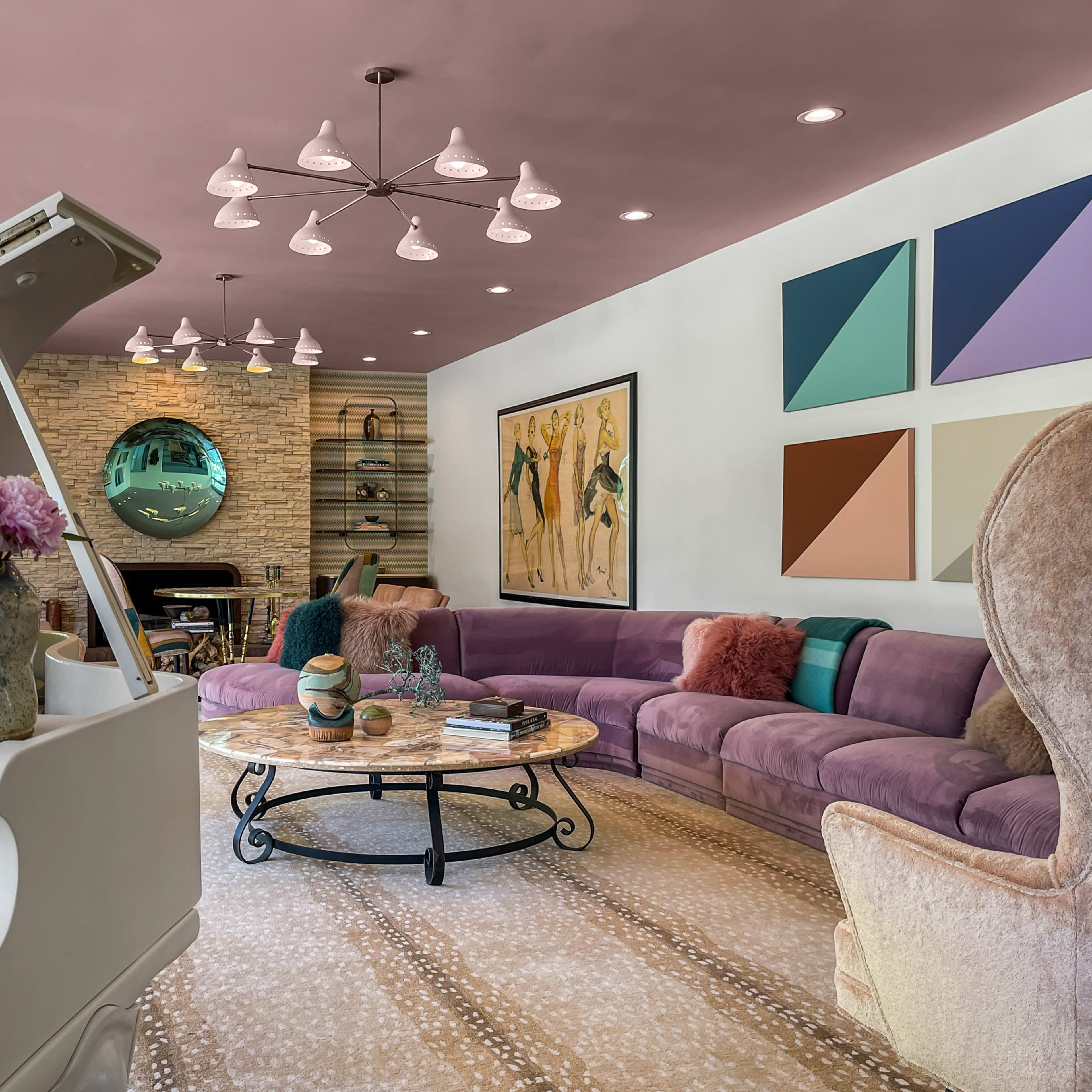 A modern living room with a pink ceiling, a grand piano, a large purple sectional sofa, and colorful artwork on the walls.