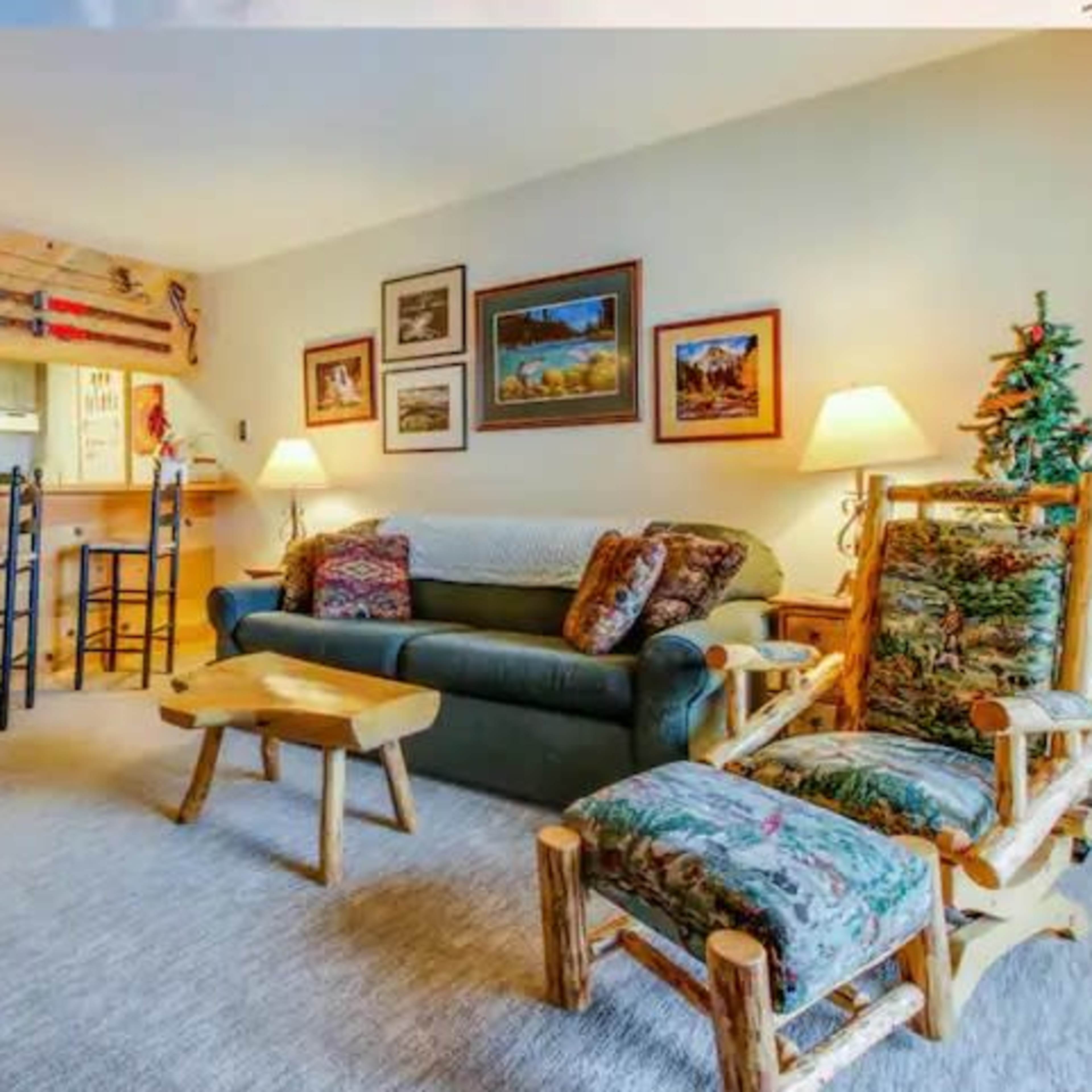 The living room features a sofa, two wooden chairs, a coffee table, and several framed pictures on the walls.