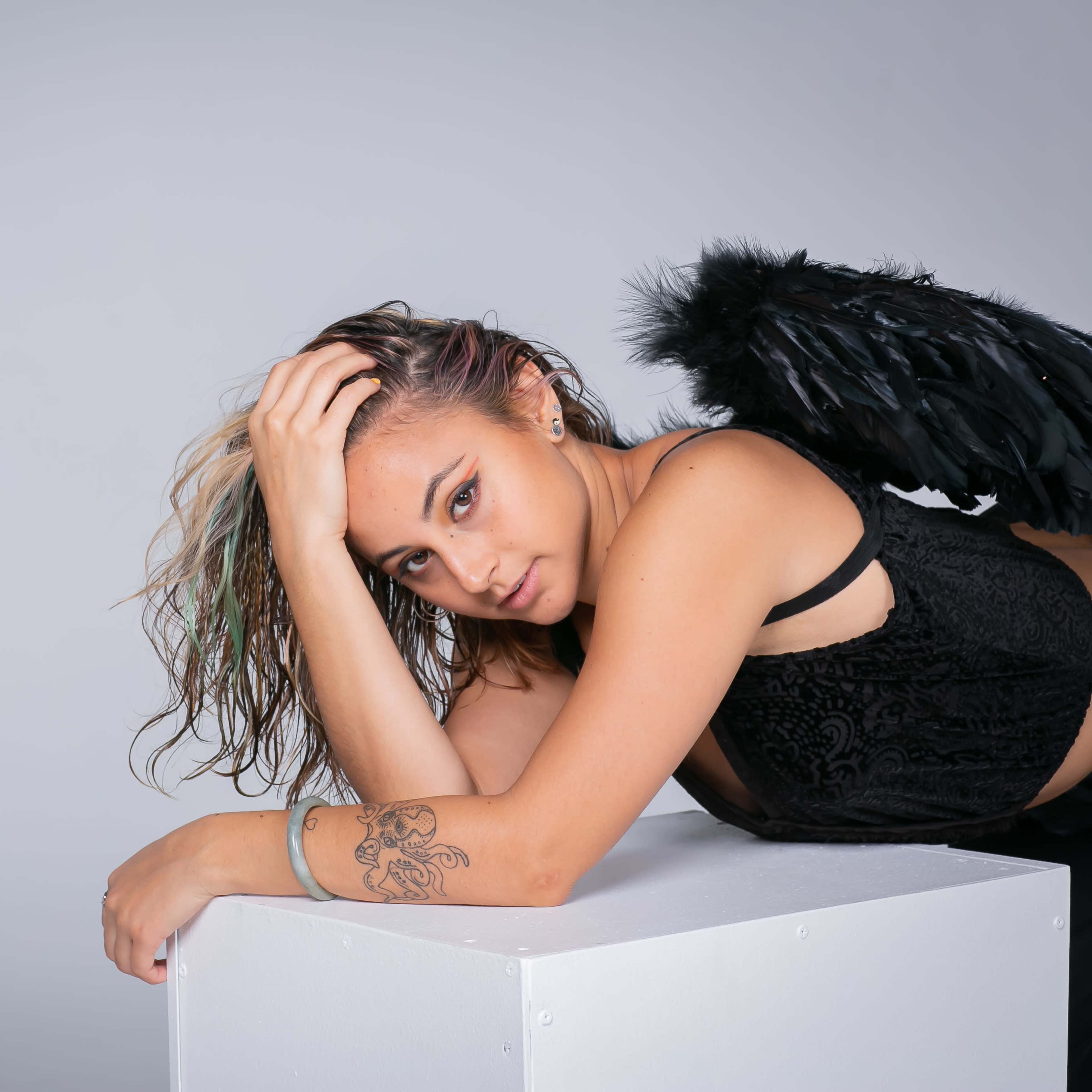 A person with wings lies on a white pedestal against a gray background.