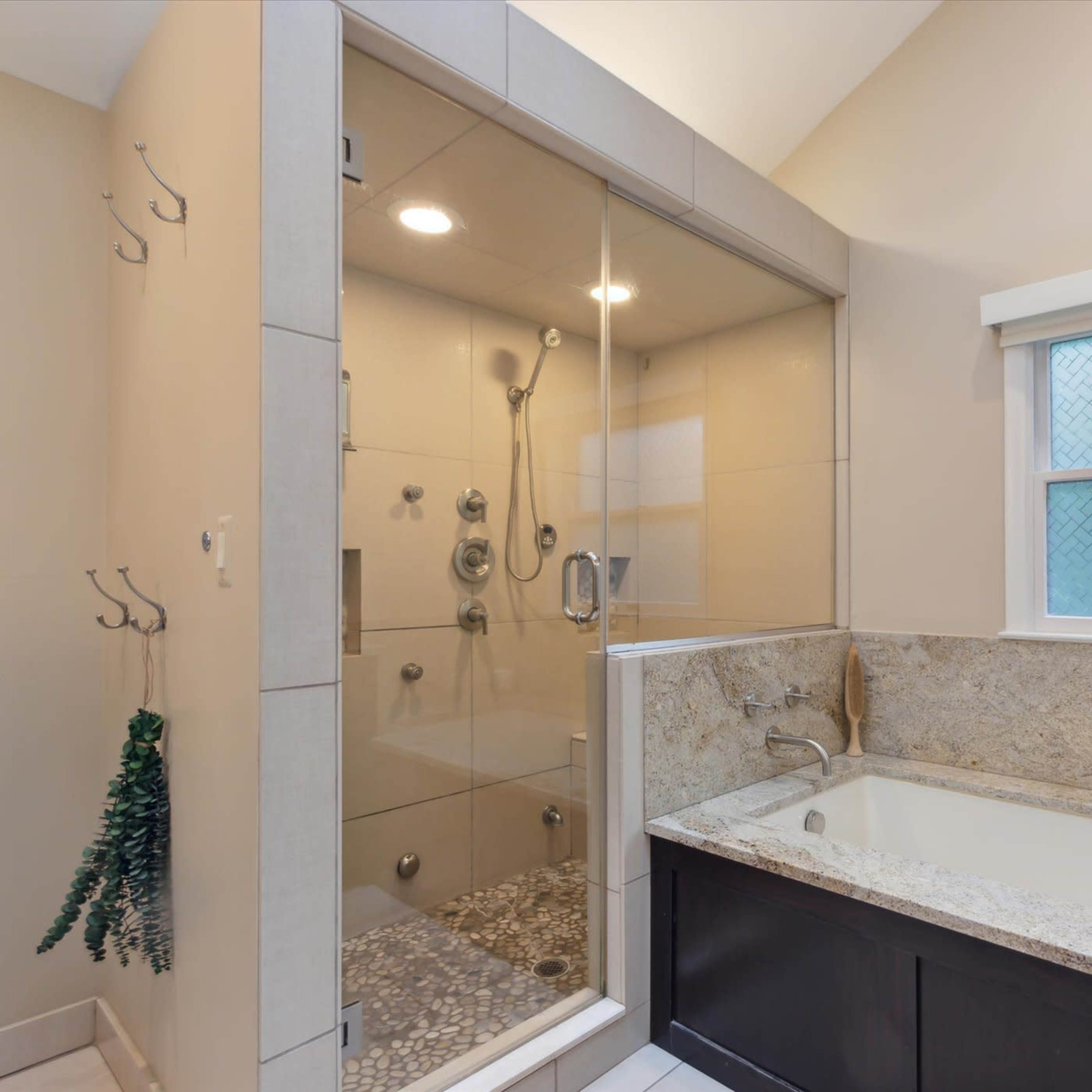A bathroom featuring a glass-enclosed shower and a freestanding bathtub next to a window.