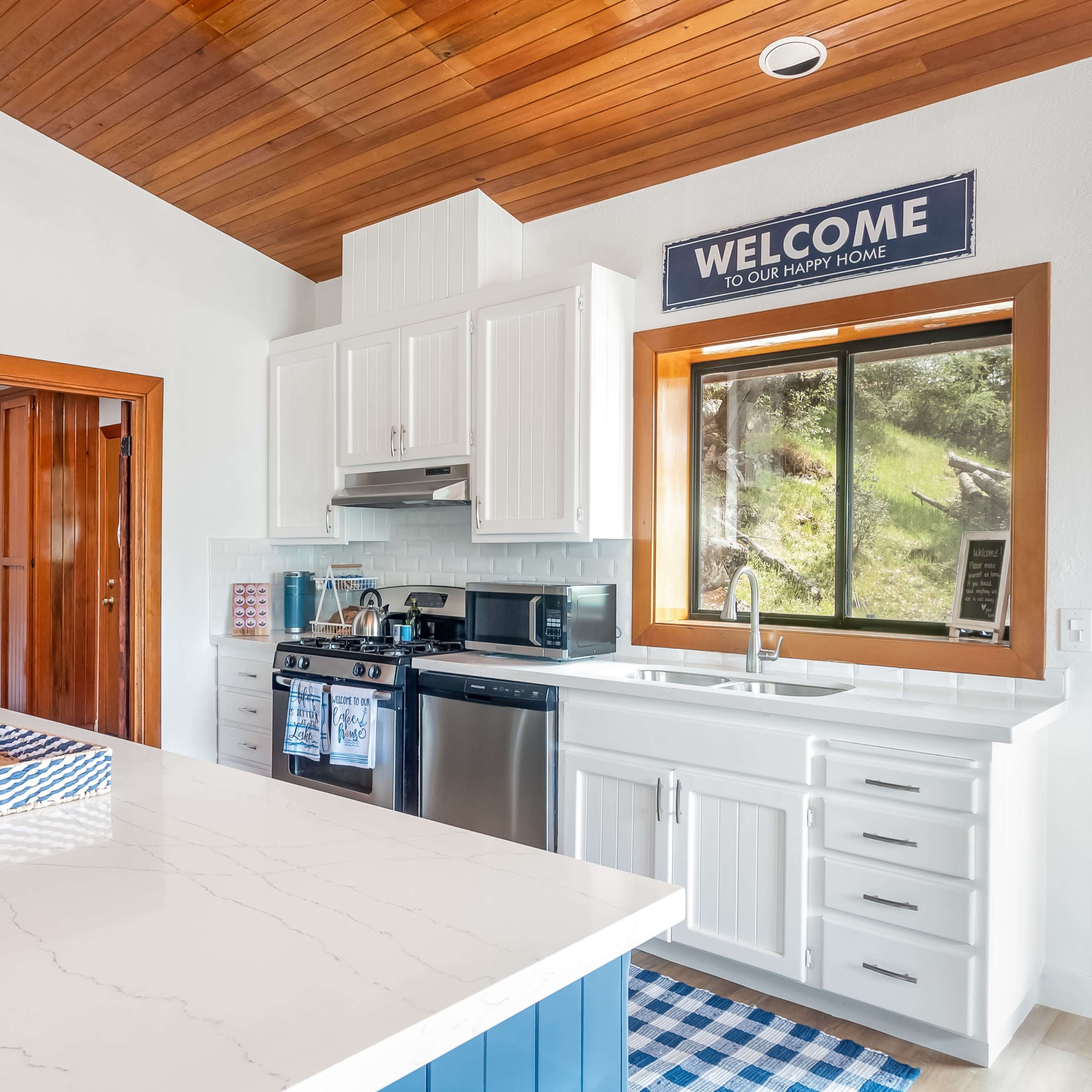 A modern kitchen with white cabinetry, a stainless steel oven, and a large island featuring a marble countertop.