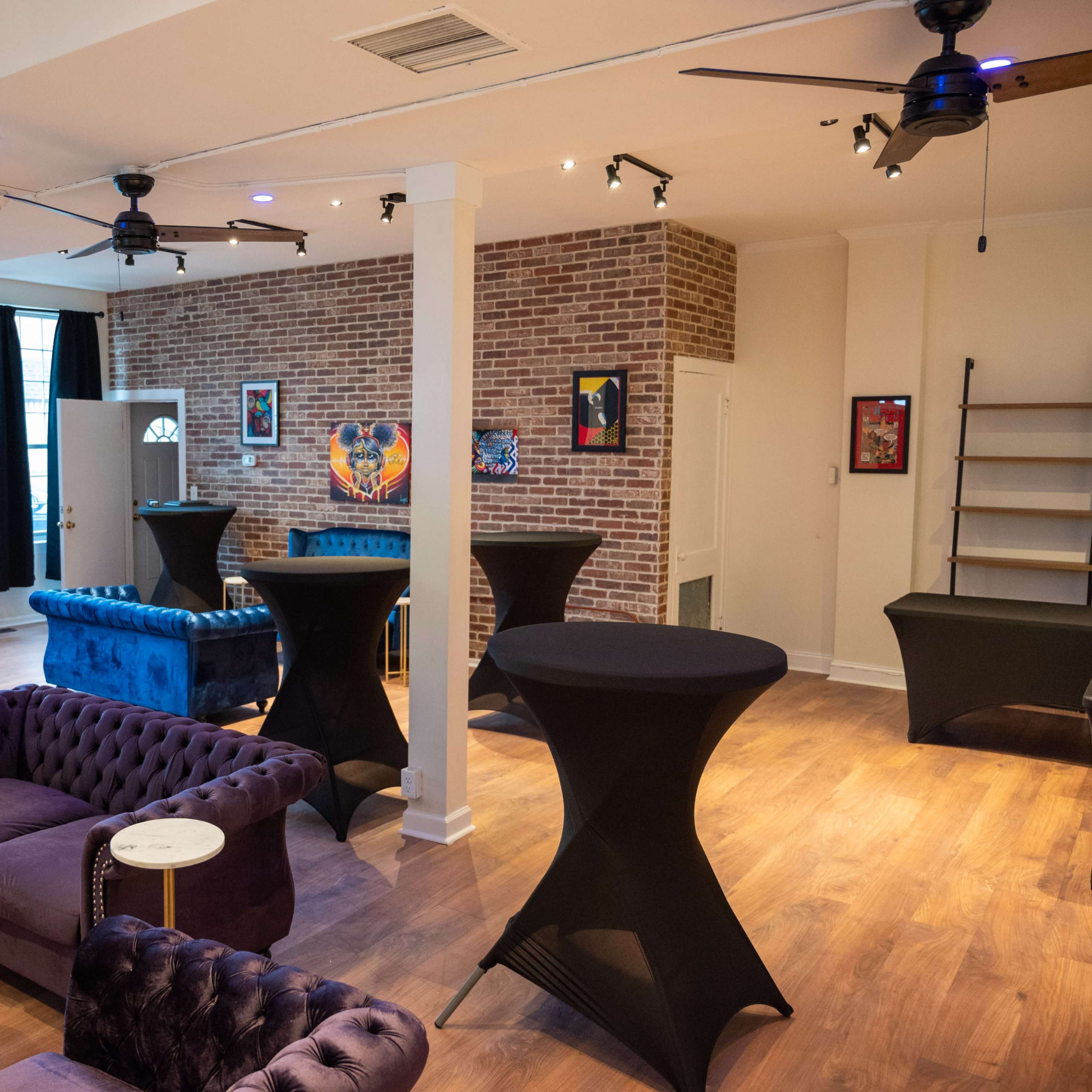 A spacious, modern event space with a mix of plush seating, high tables, and large windows.