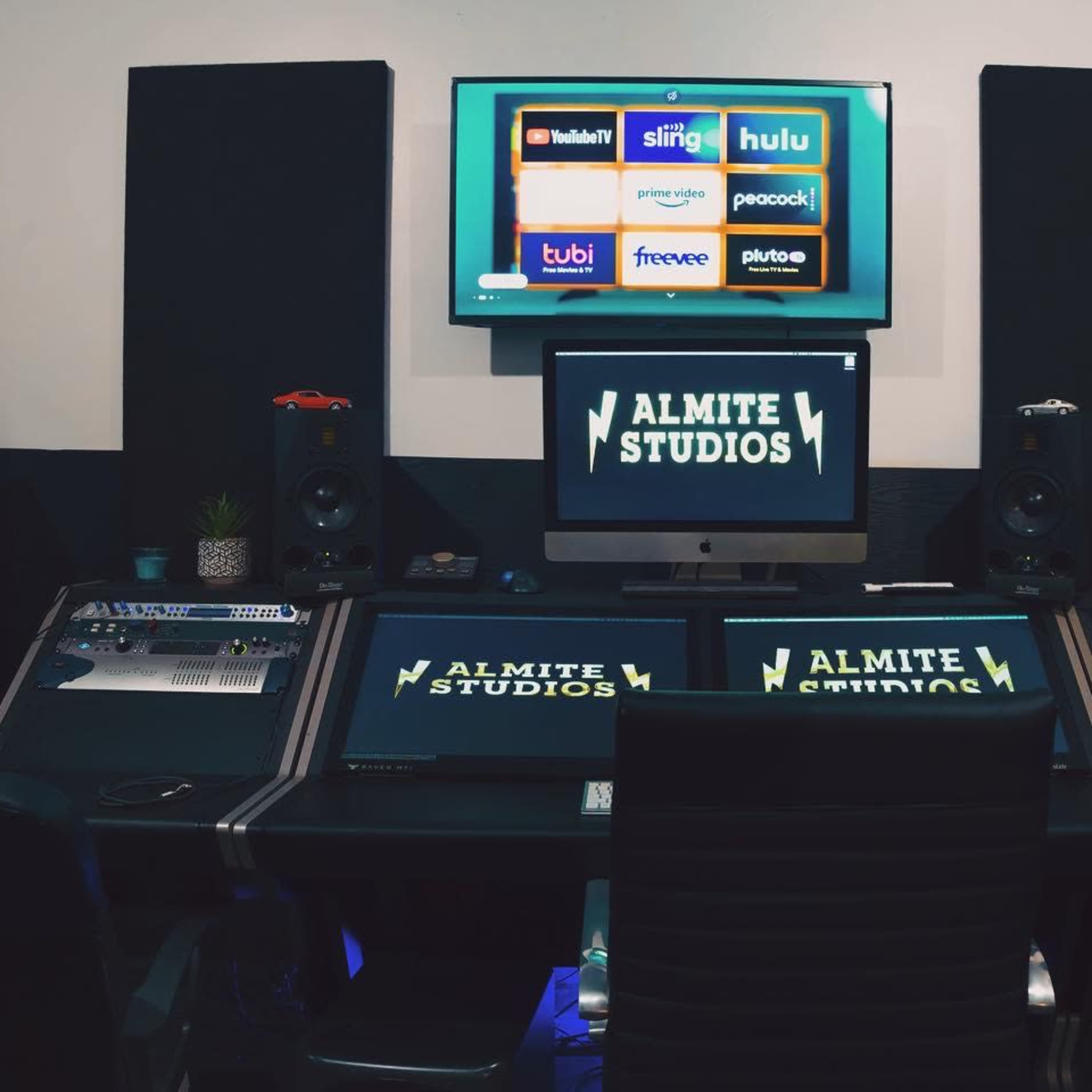 A modern sound recording studio with multiple screens, audio equipment, and branded signage for "ALMITE STUDIOS."