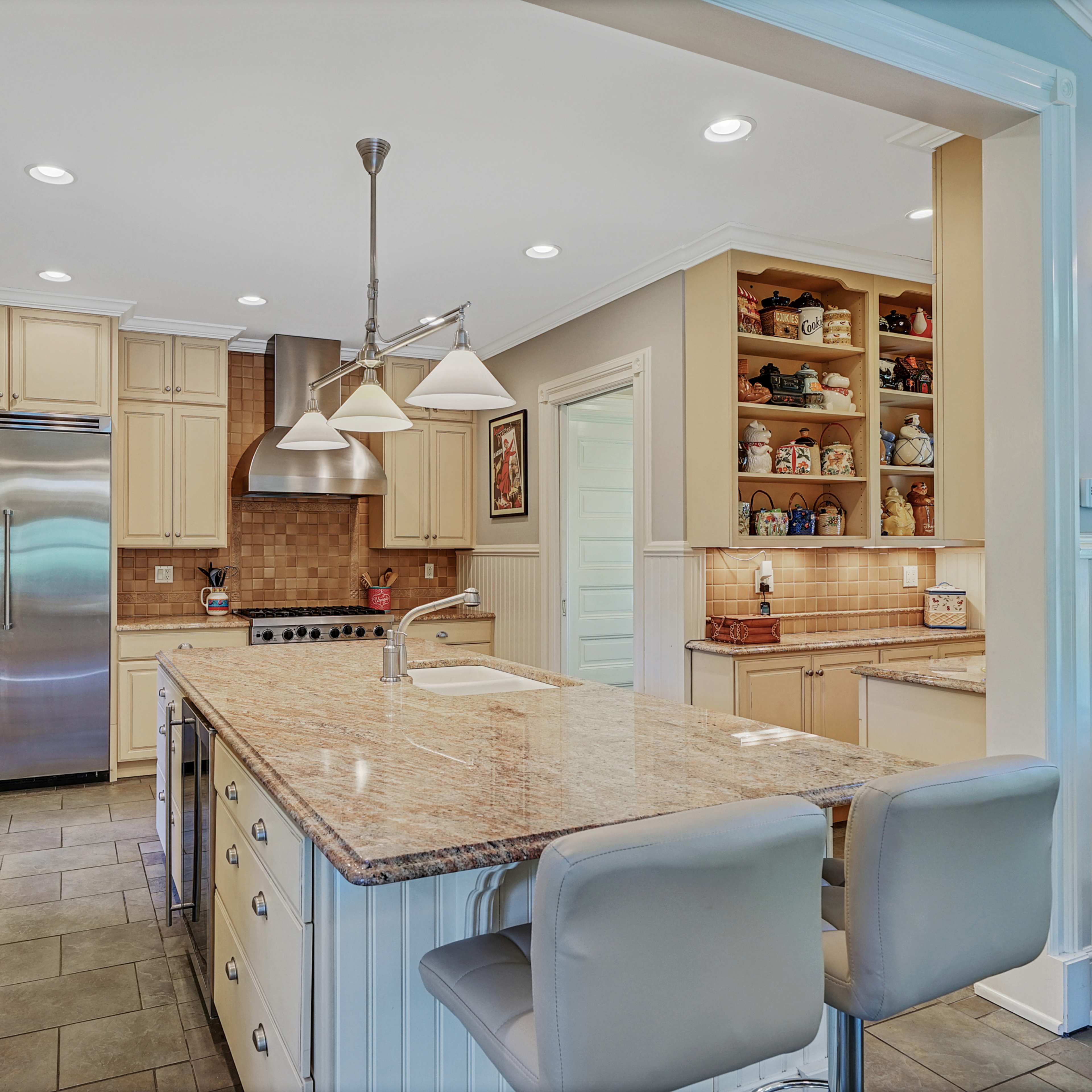 The kitchen features a large island with bar seating, stainless steel appliances, and cream-colored cabinetry.