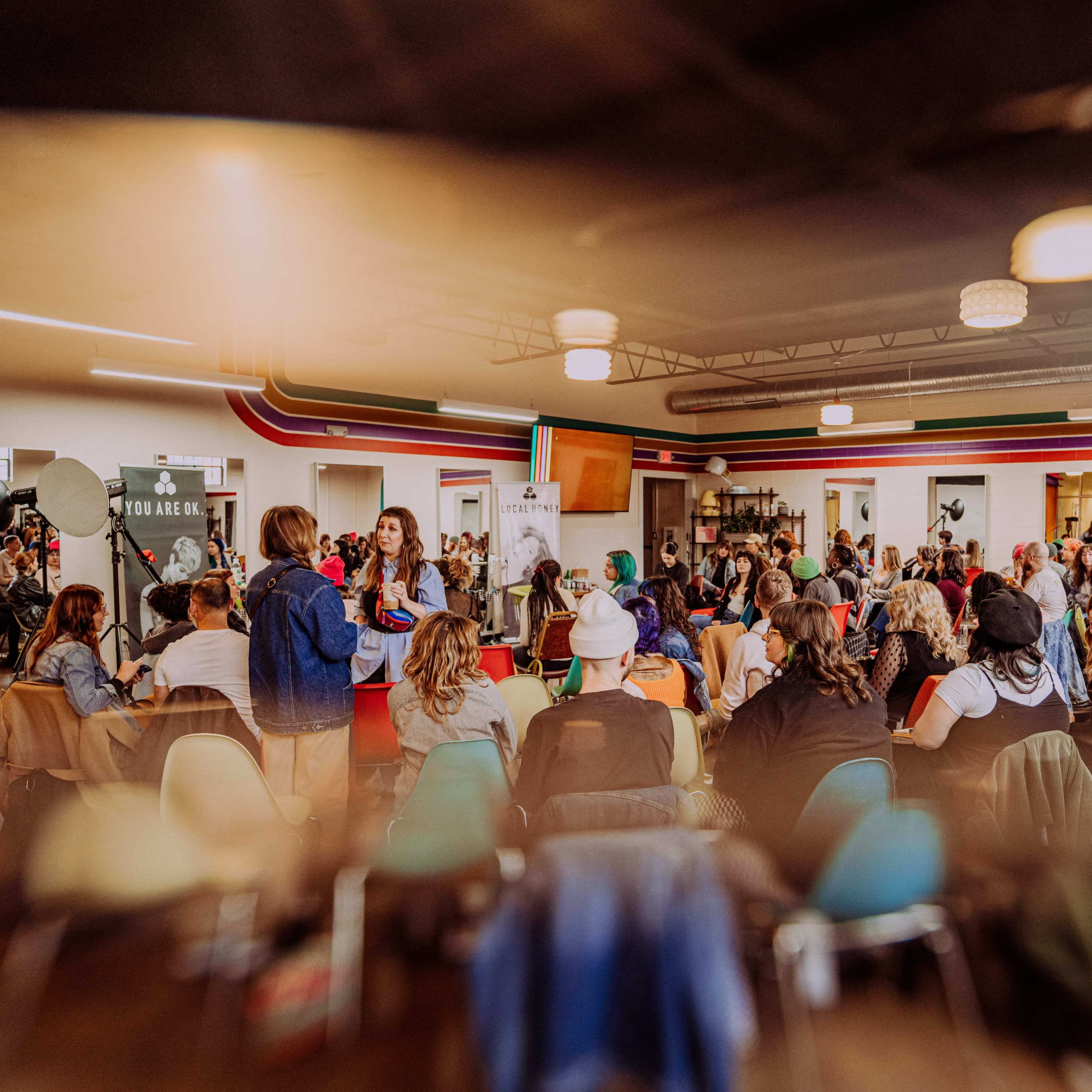 A large group of people is gathered in a brightly colored room for an event or meeting.