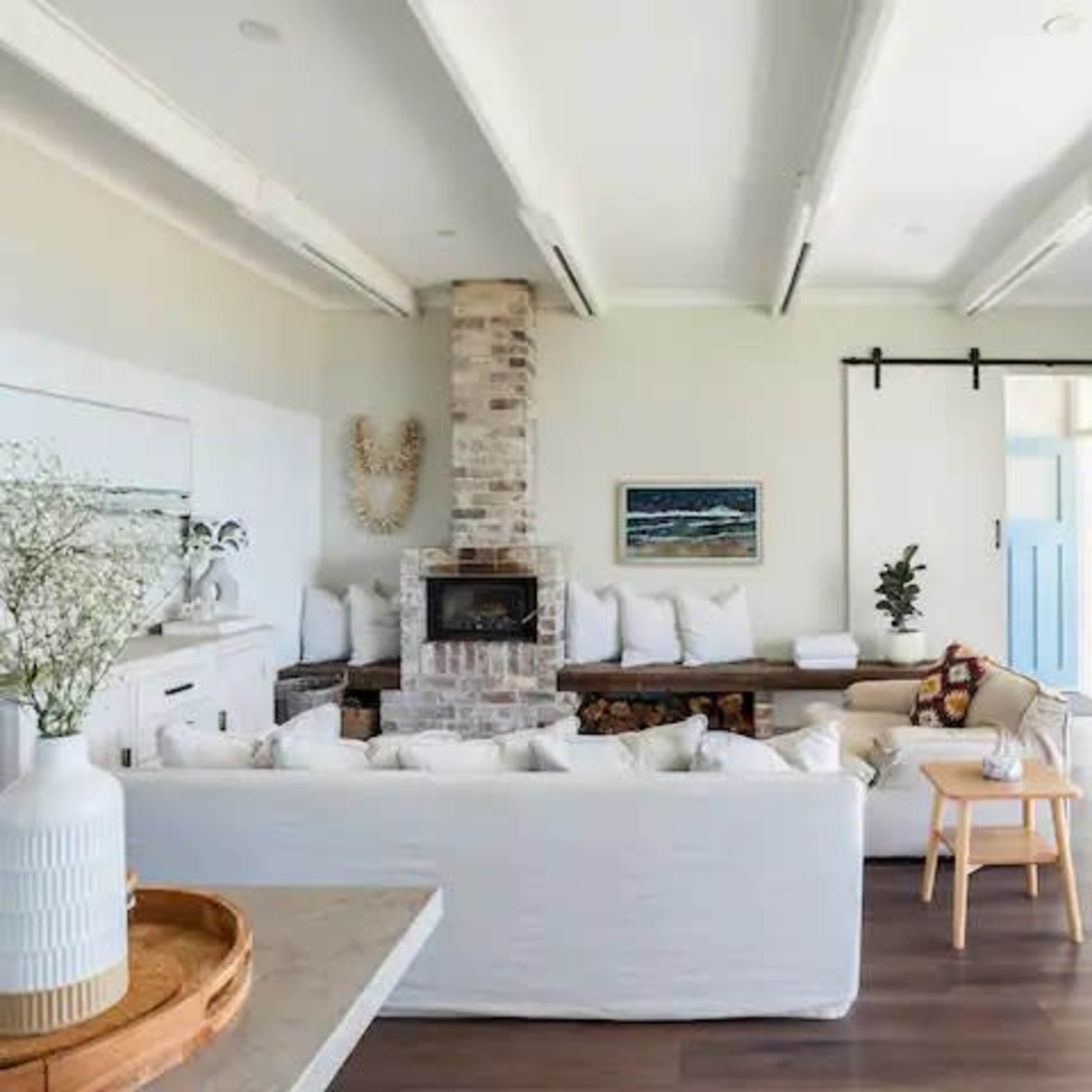 A bright living room featuring a brick fireplace, a large white sofa, and a blue door that opens to an outdoor area.