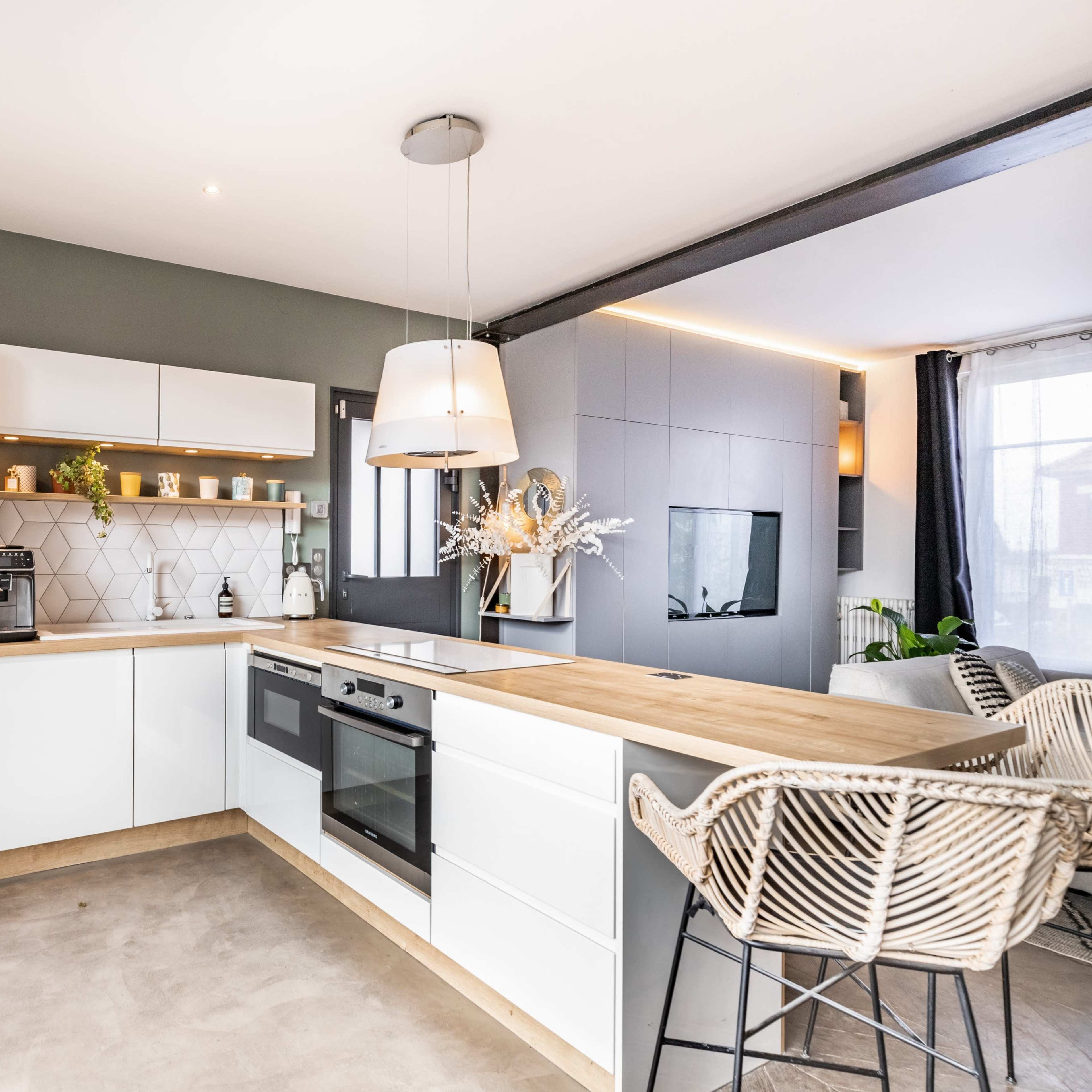 A modern kitchen with white cabinetry, a wooden countertop, and a seating area featuring wicker bar stools.