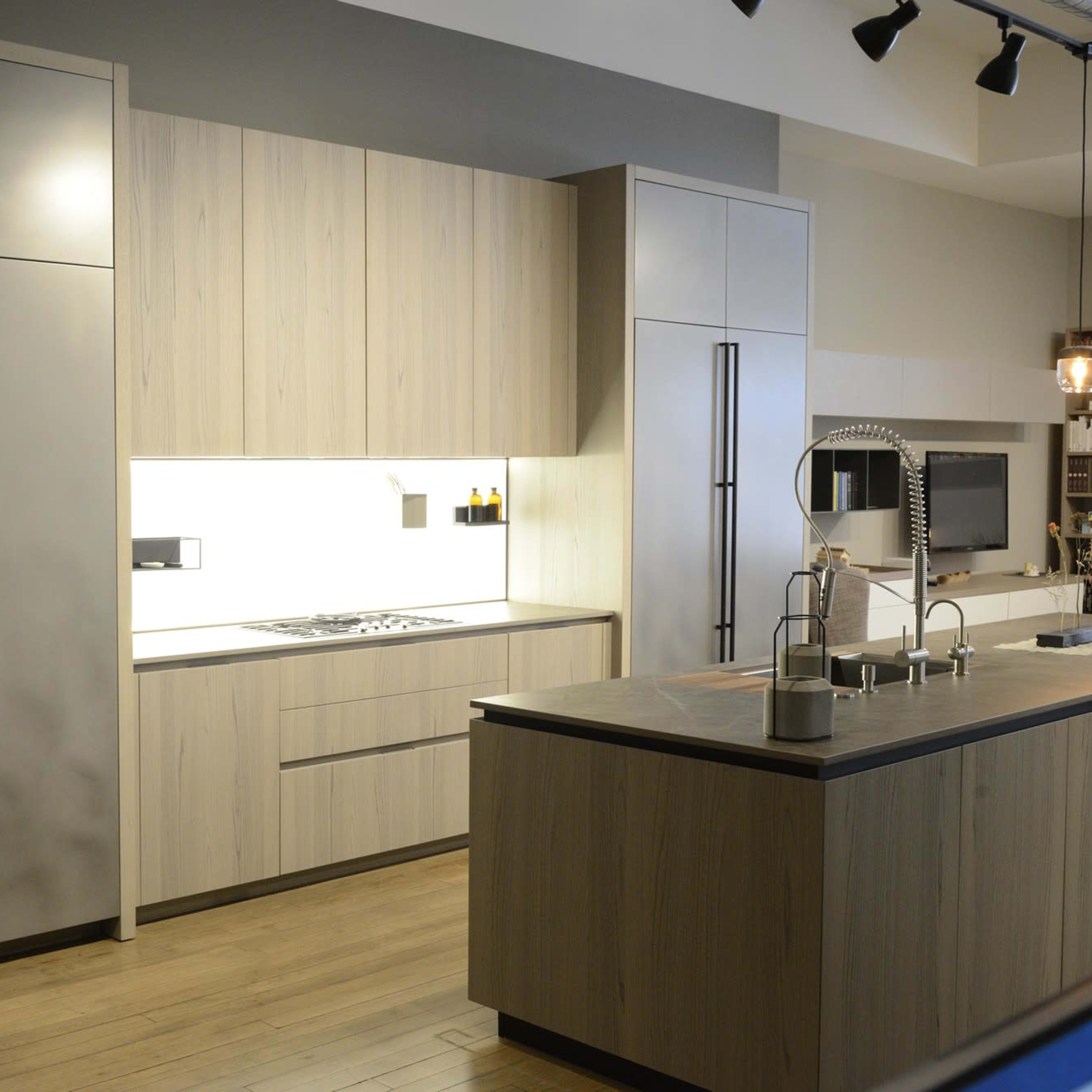 A modern kitchen with wooden cabinetry, a large stainless steel refrigerator, and an island with a sink.