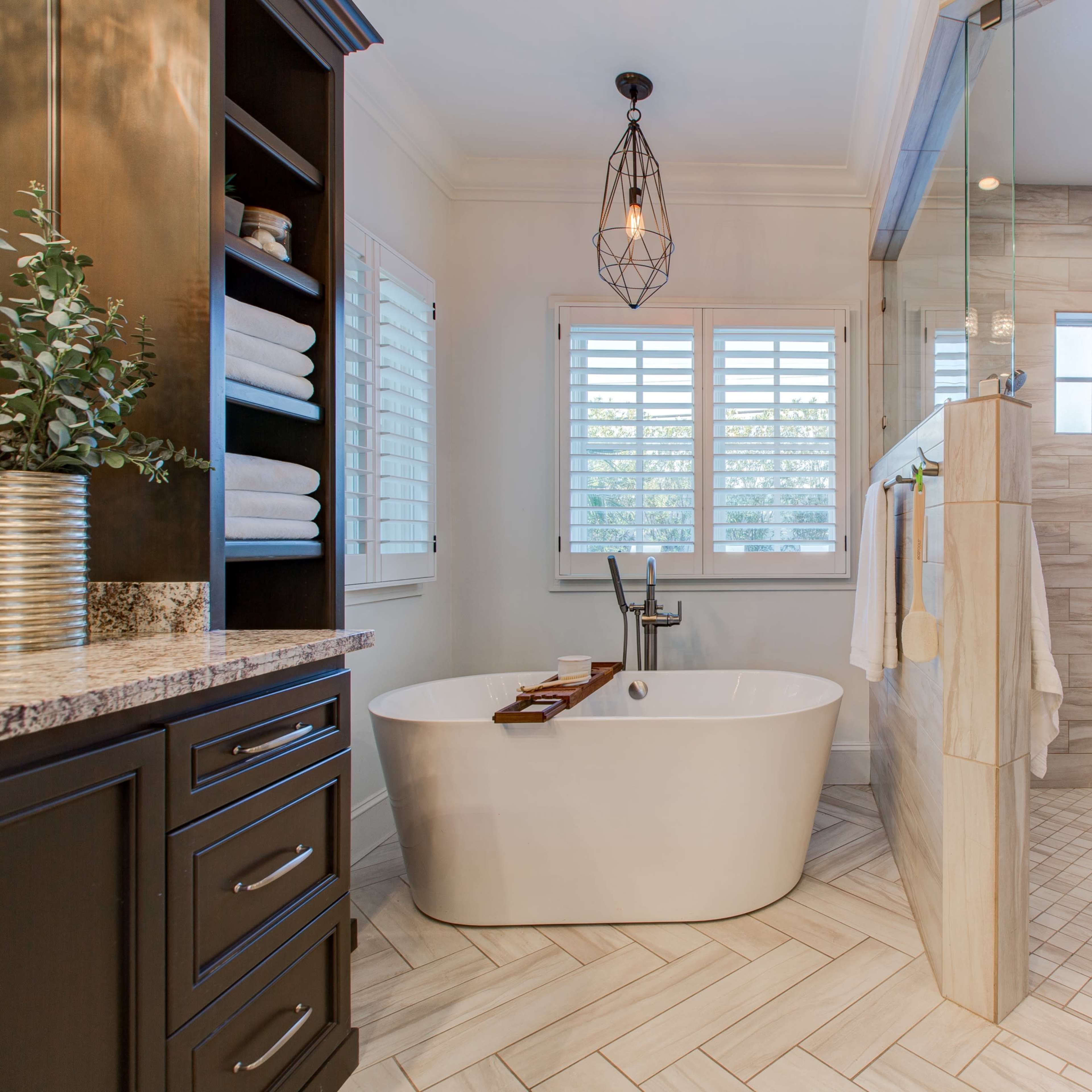 The kitchen features a large marble island with black cabinetry and a brick accent wall, overlooking a living area with a television and a yellow sofa.