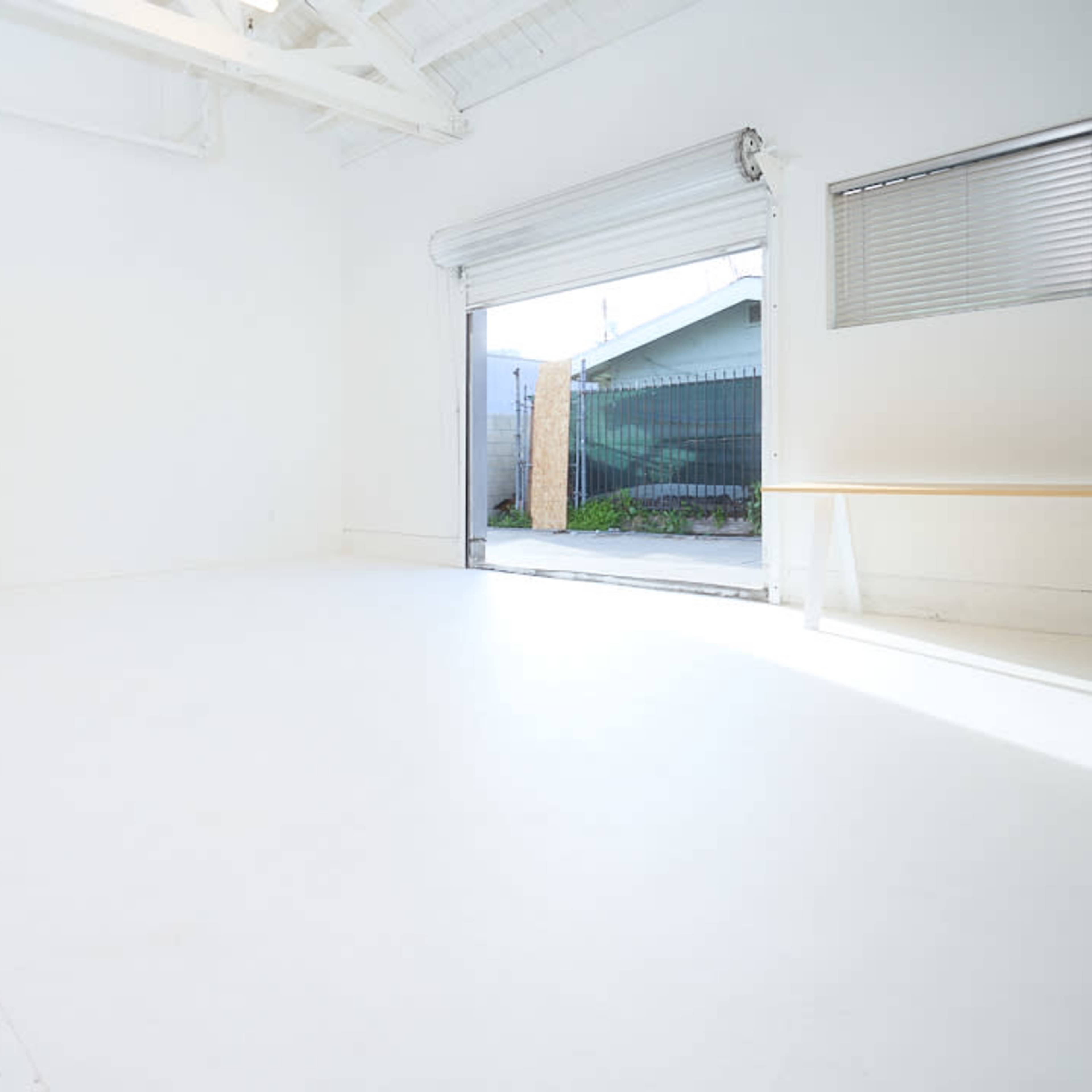 A bright, empty room with white walls and a large open door leading to an outdoor area.