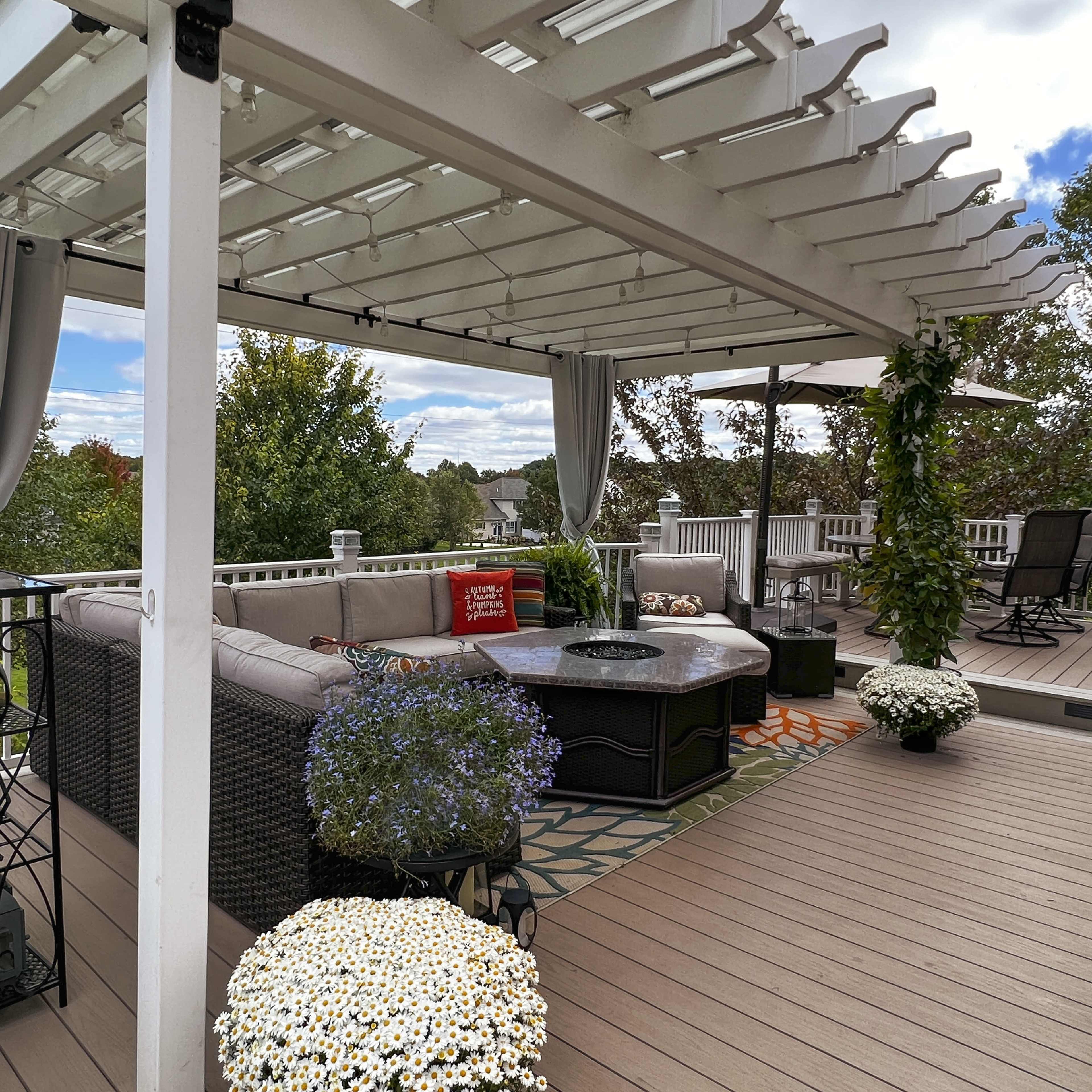 A spacious outdoor patio with a covered seating area, potted plants, and a circular fire pit.