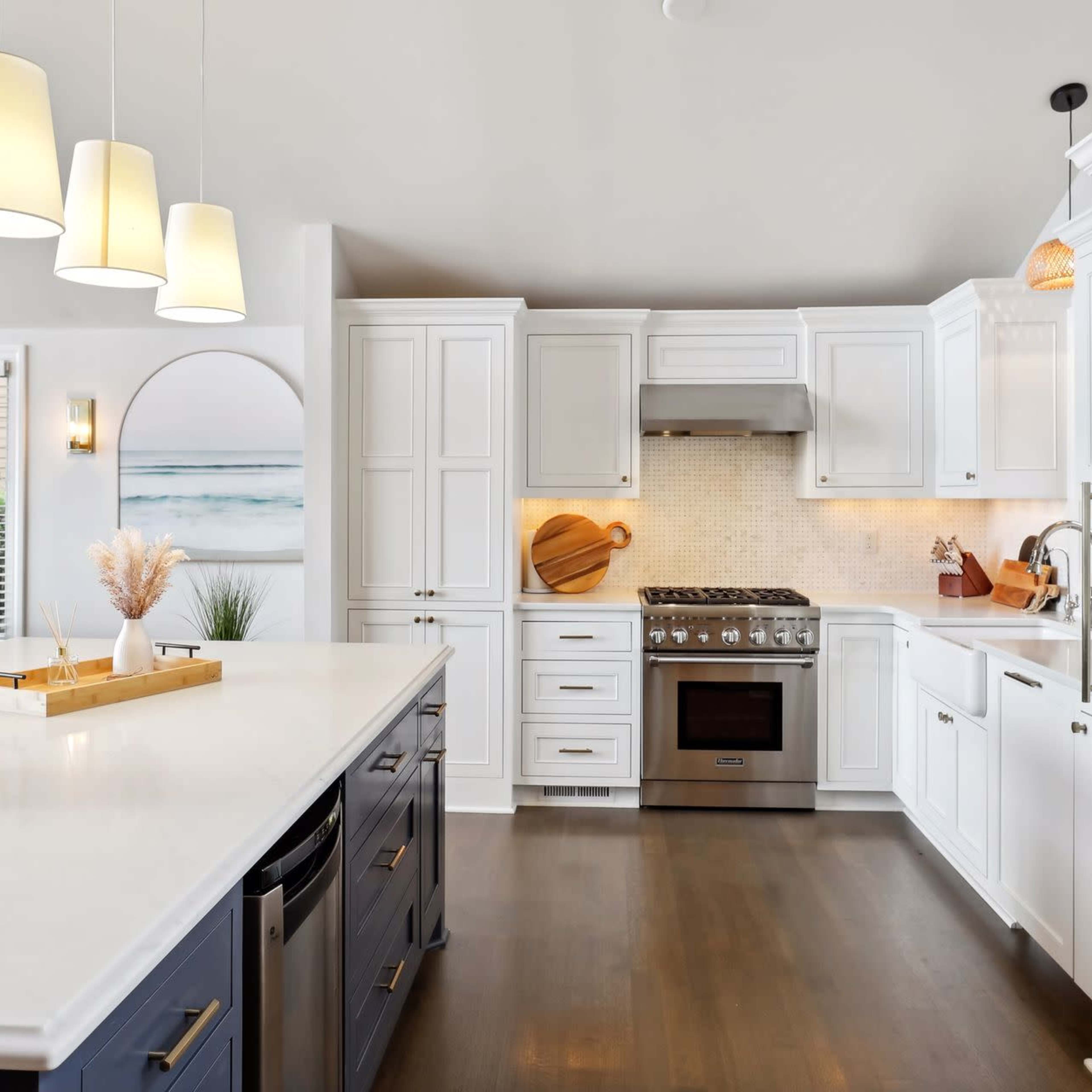 A modern kitchen with white cabinets, a stainless steel stove, and a large island with a contrasting blue base.