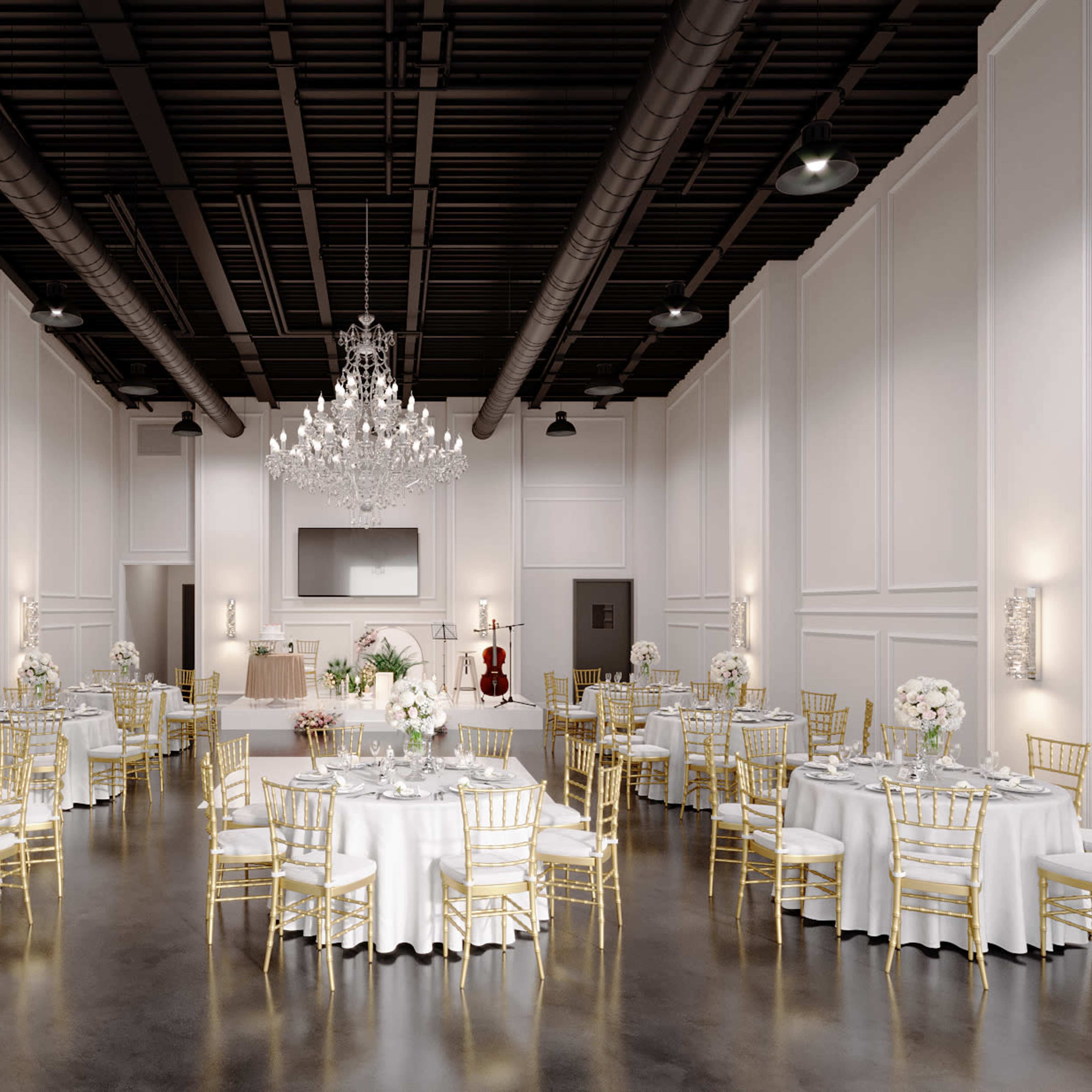 An elegantly decorated banquet hall with round tables set for a formal event, featuring white tablecloths and gold chairs, illuminated by a large chandelier.