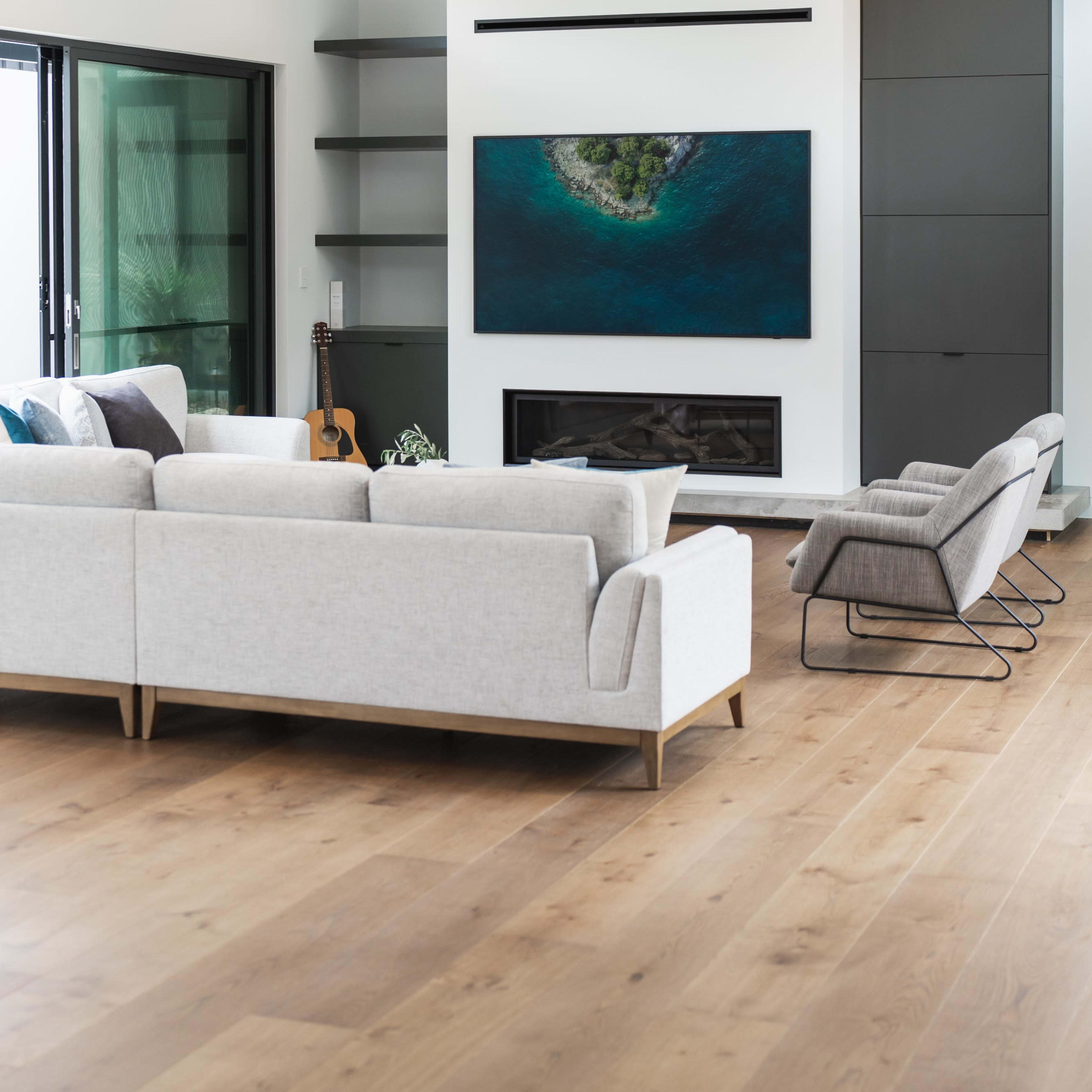 A modern living room features a gray sectional sofa, a sleek fireplace, and a large television mounted on the wall.