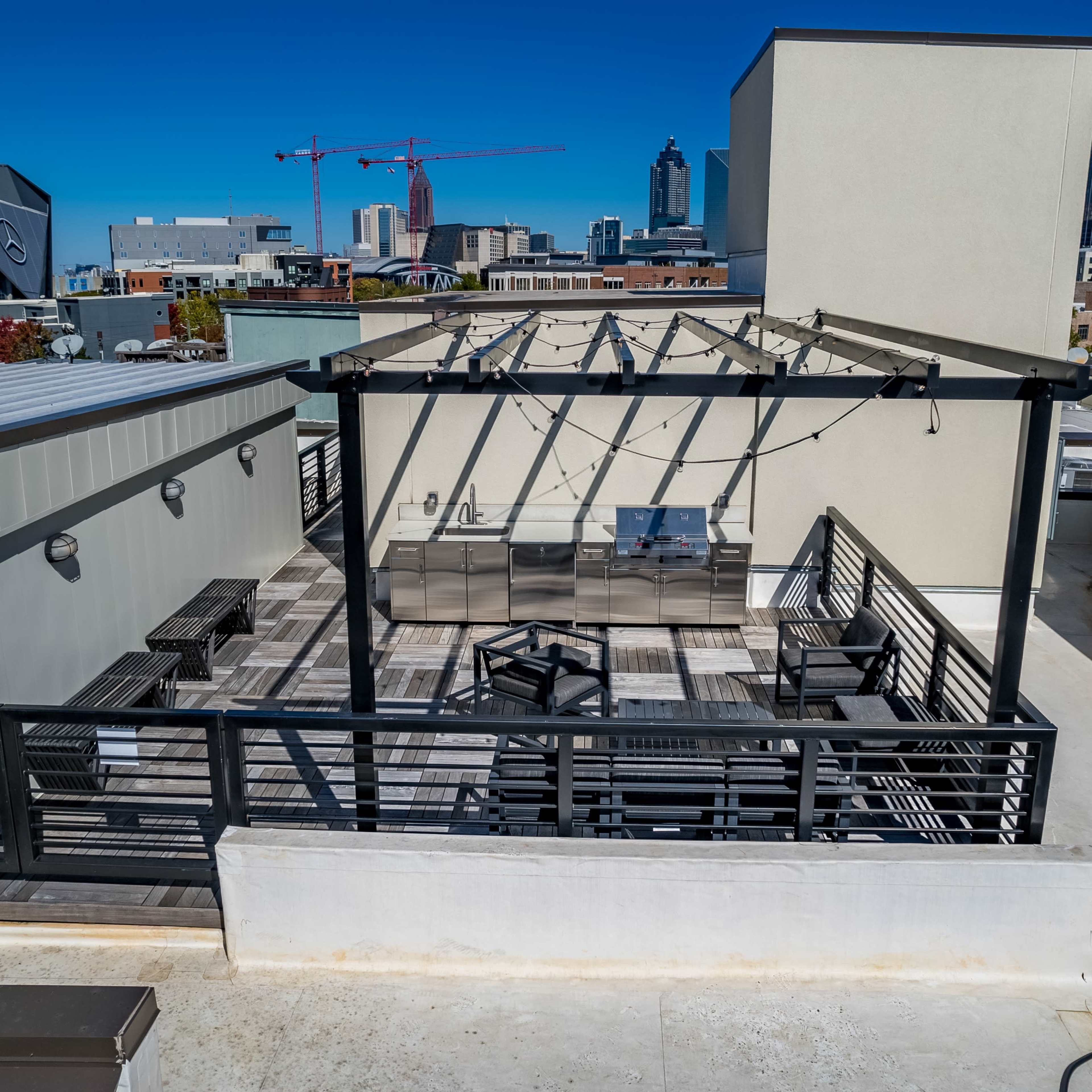 A rooftop patio with an outdoor kitchen and seating area, surrounded by a city skyline.
