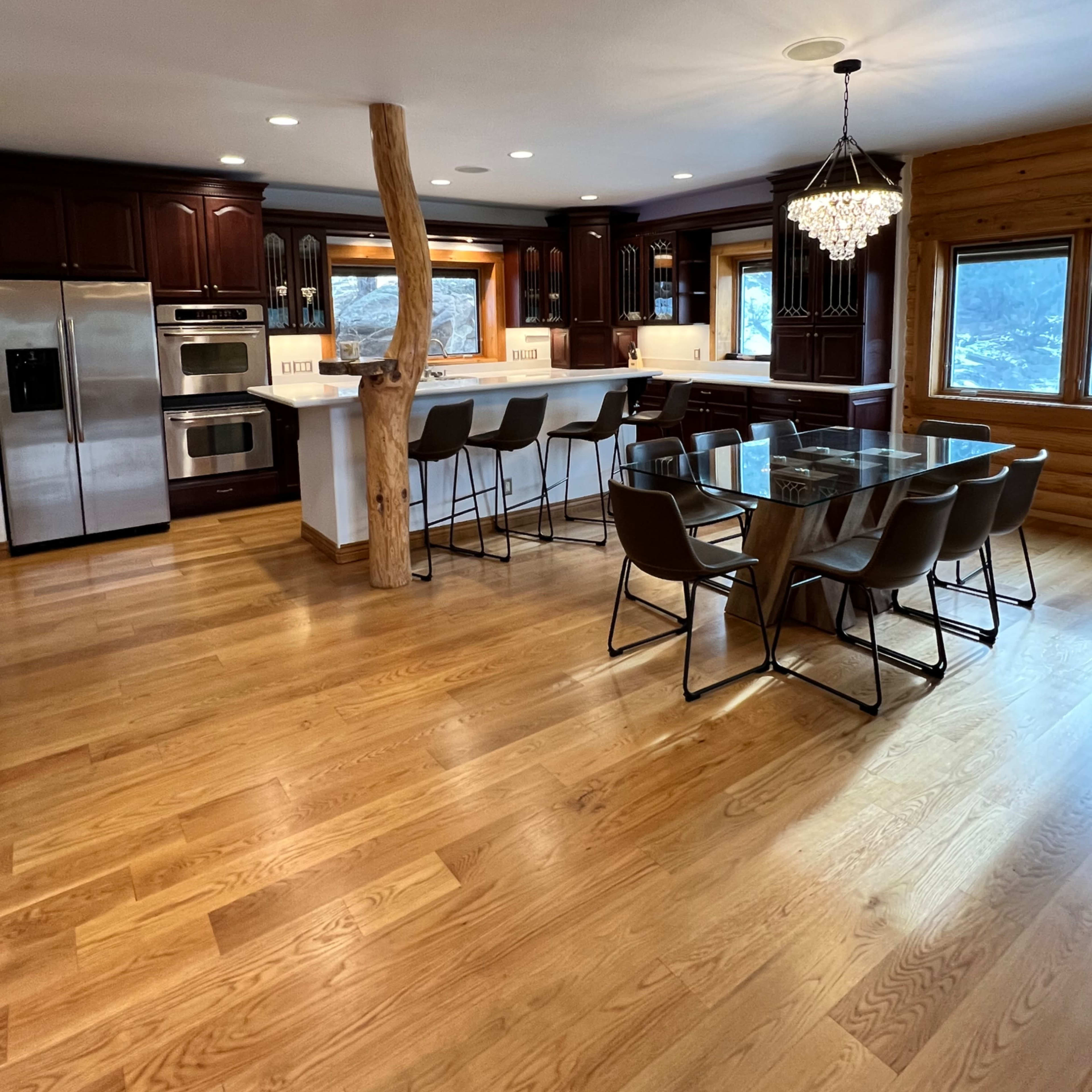 The kitchen features dark wooden cabinetry, stainless steel appliances, and a large island with seating, illuminated by a chandelier.