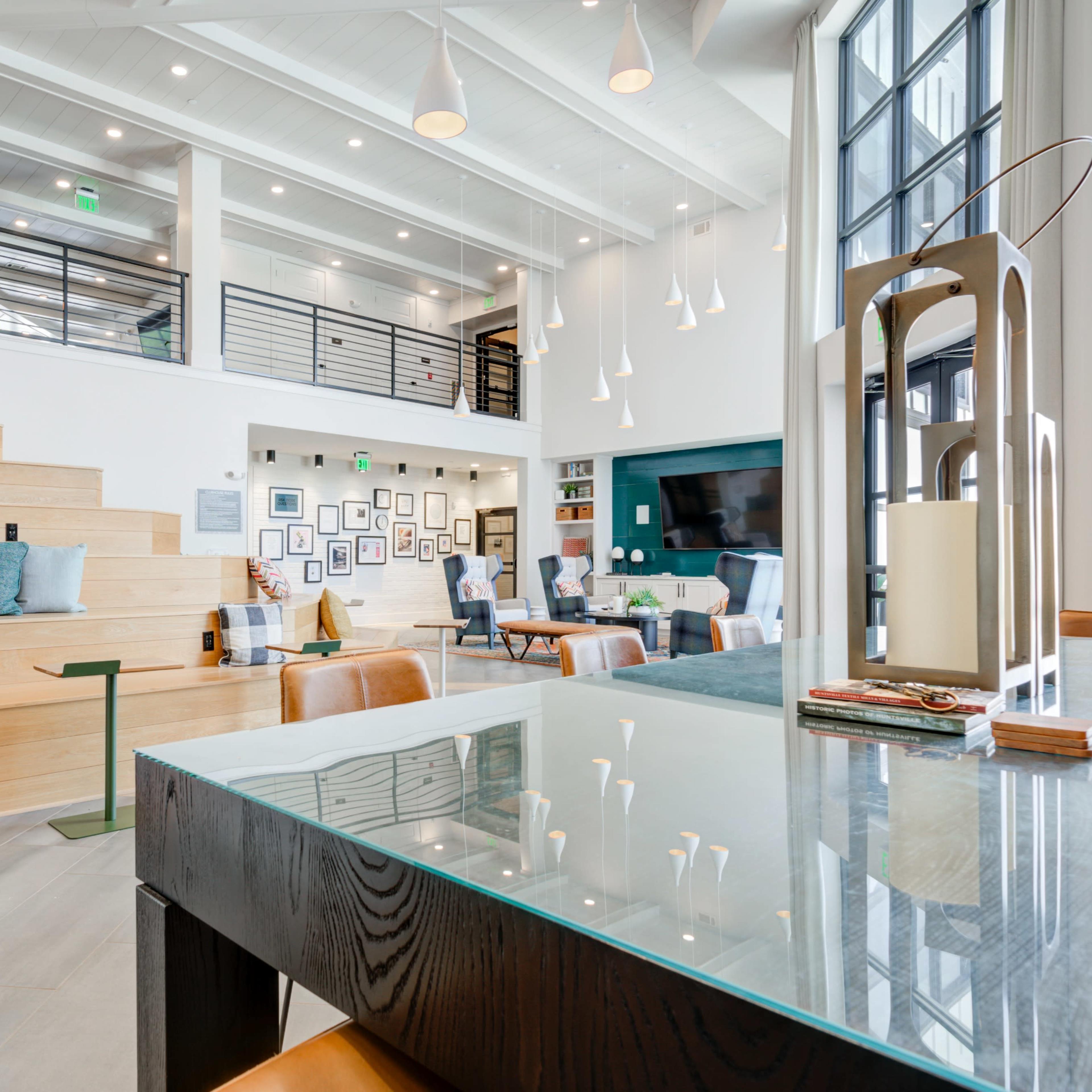 A modern interior space featuring wooden stairs, a glass table, and a wall adorned with framed photographs.