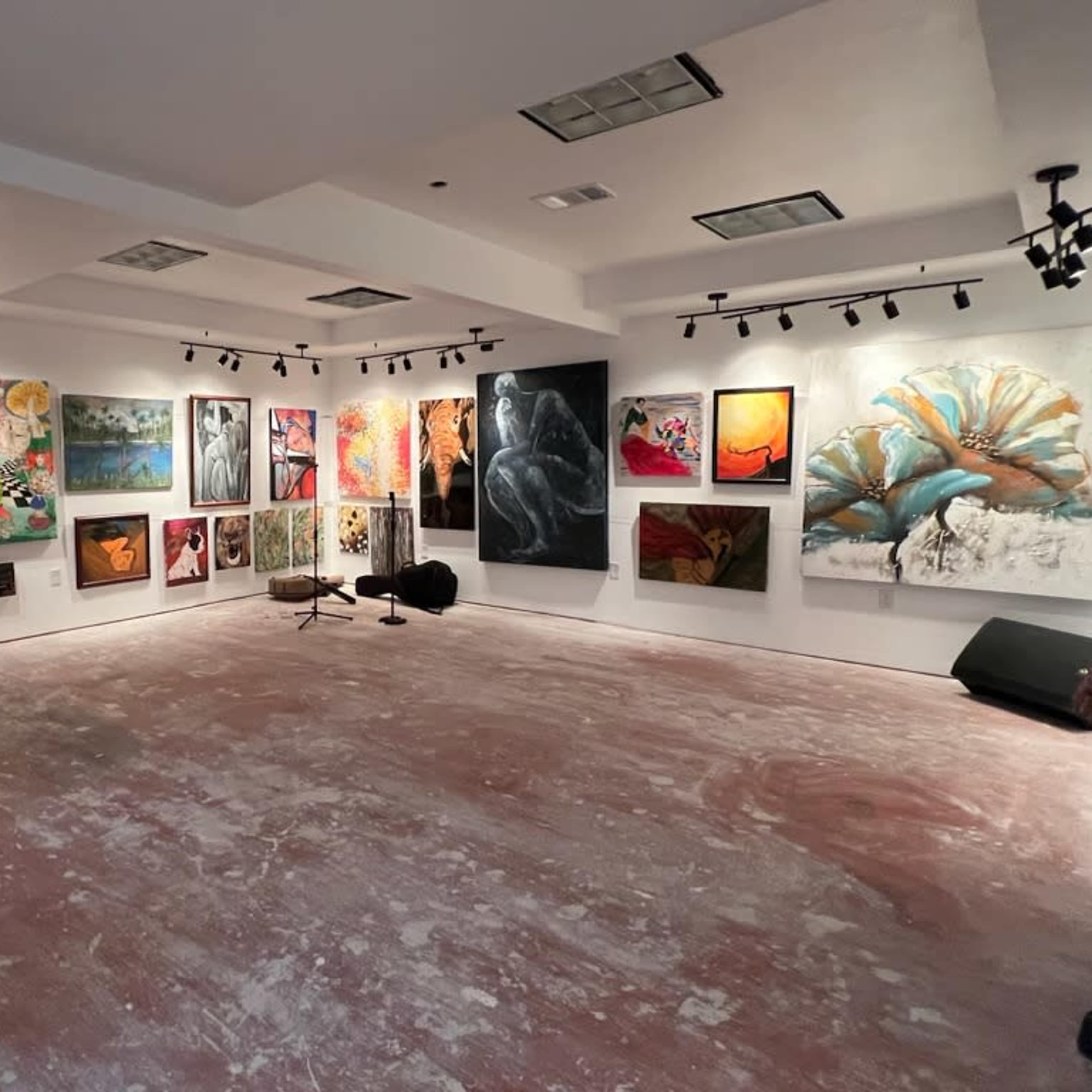 An art gallery with various paintings displayed on the walls and a bare floor.