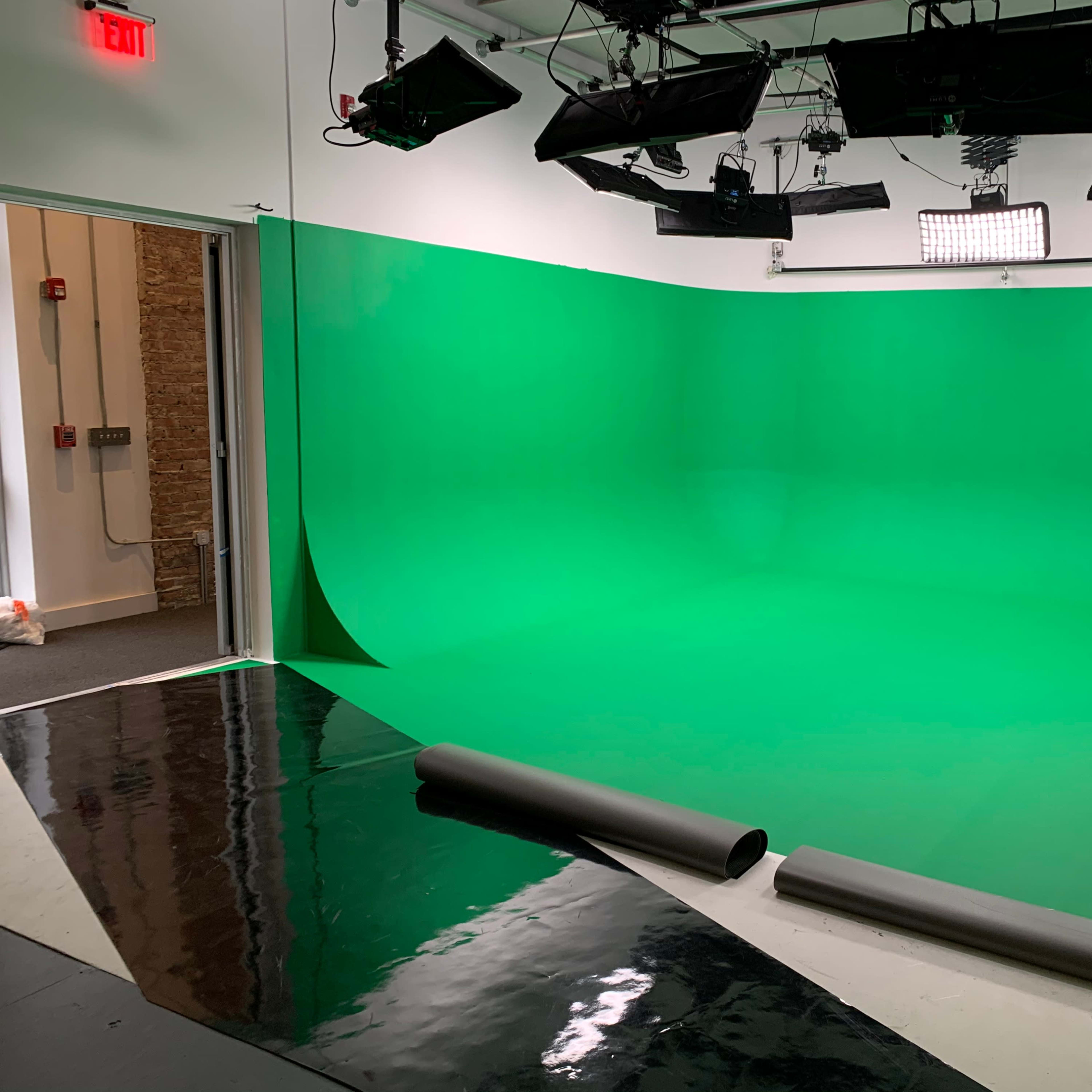 A green screen studio with bright lights and a smooth green backdrop.