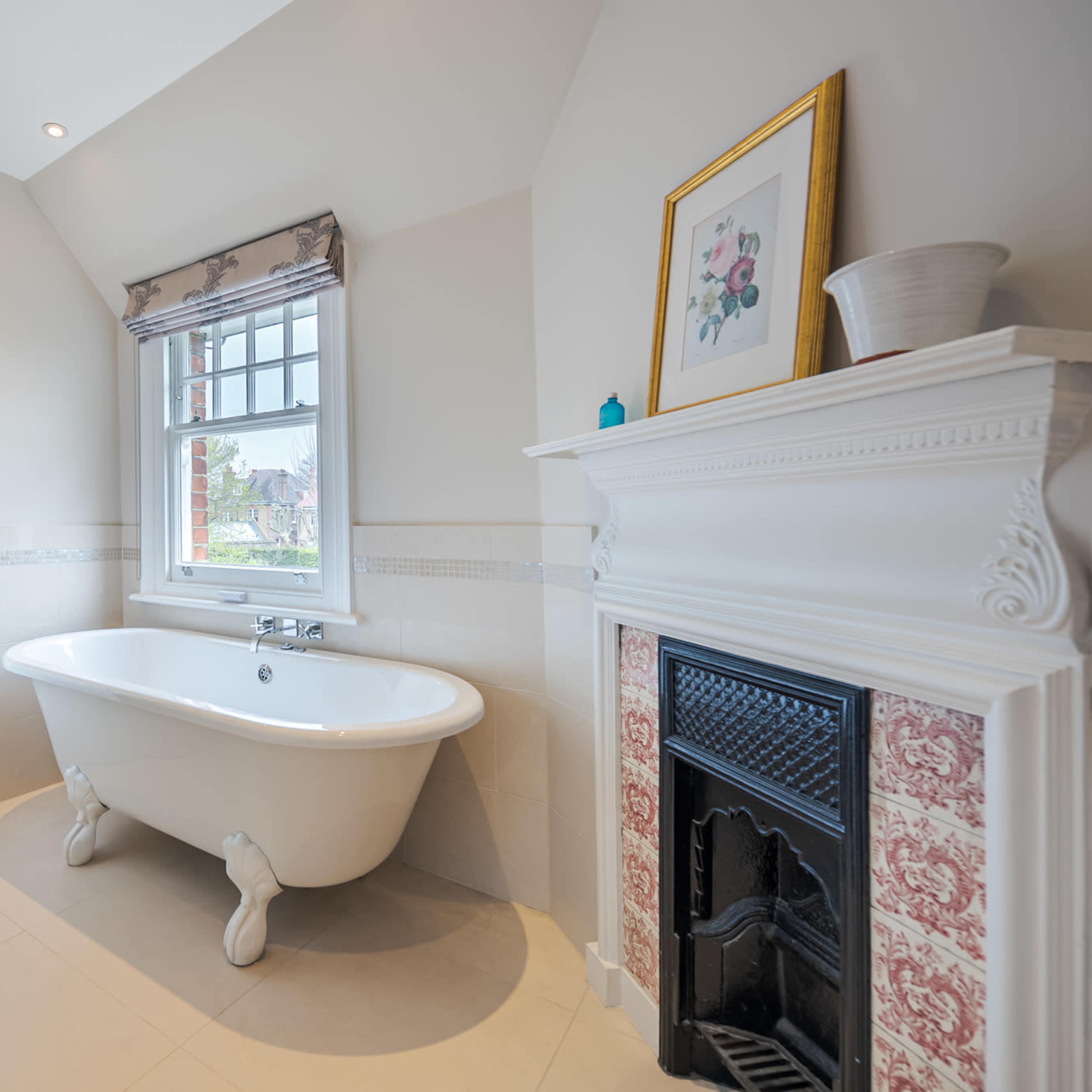 A bright bathroom featuring a freestanding bathtub, a shower enclosure, and a decorative fireplace.