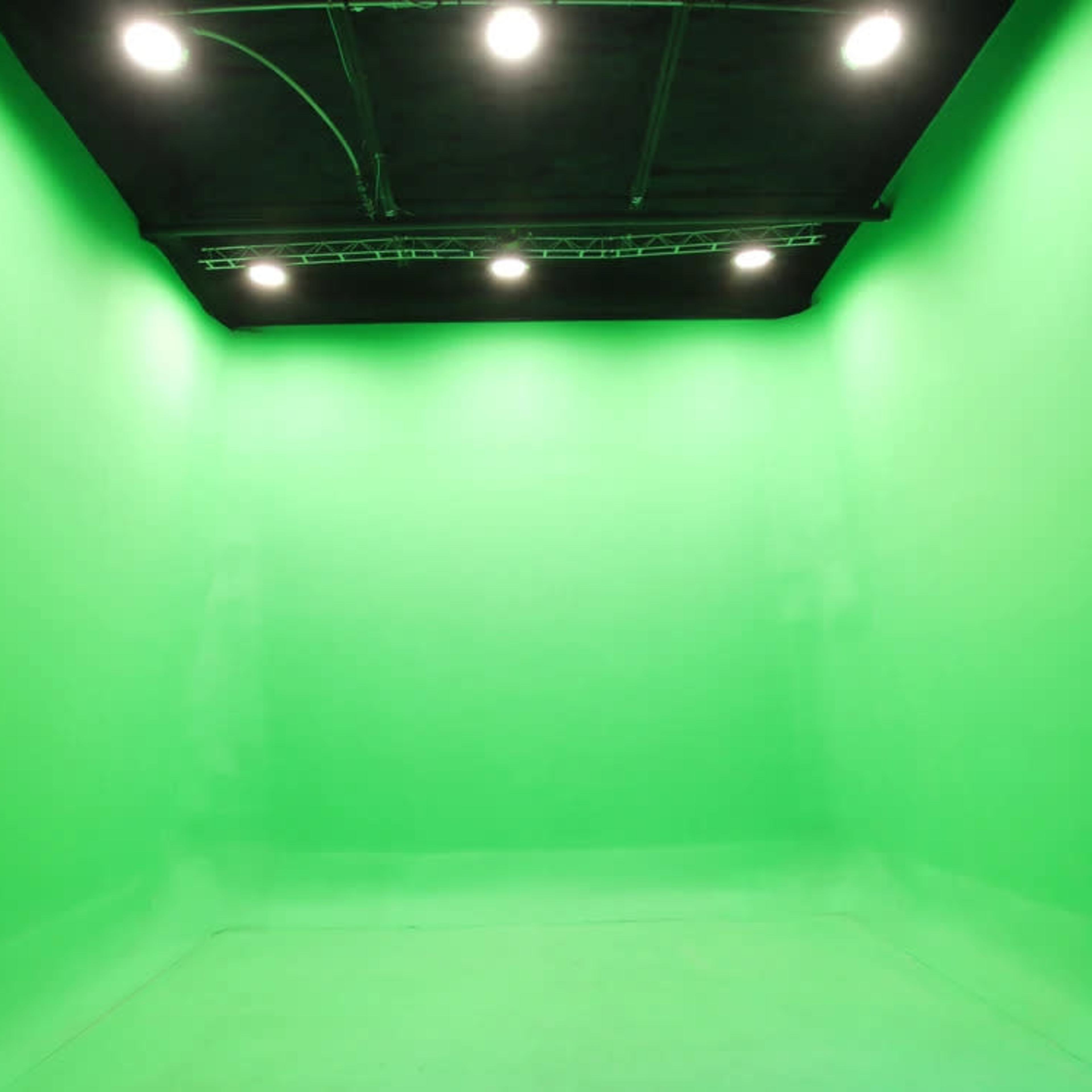 A green screen studio with bright lights attached to the ceiling.