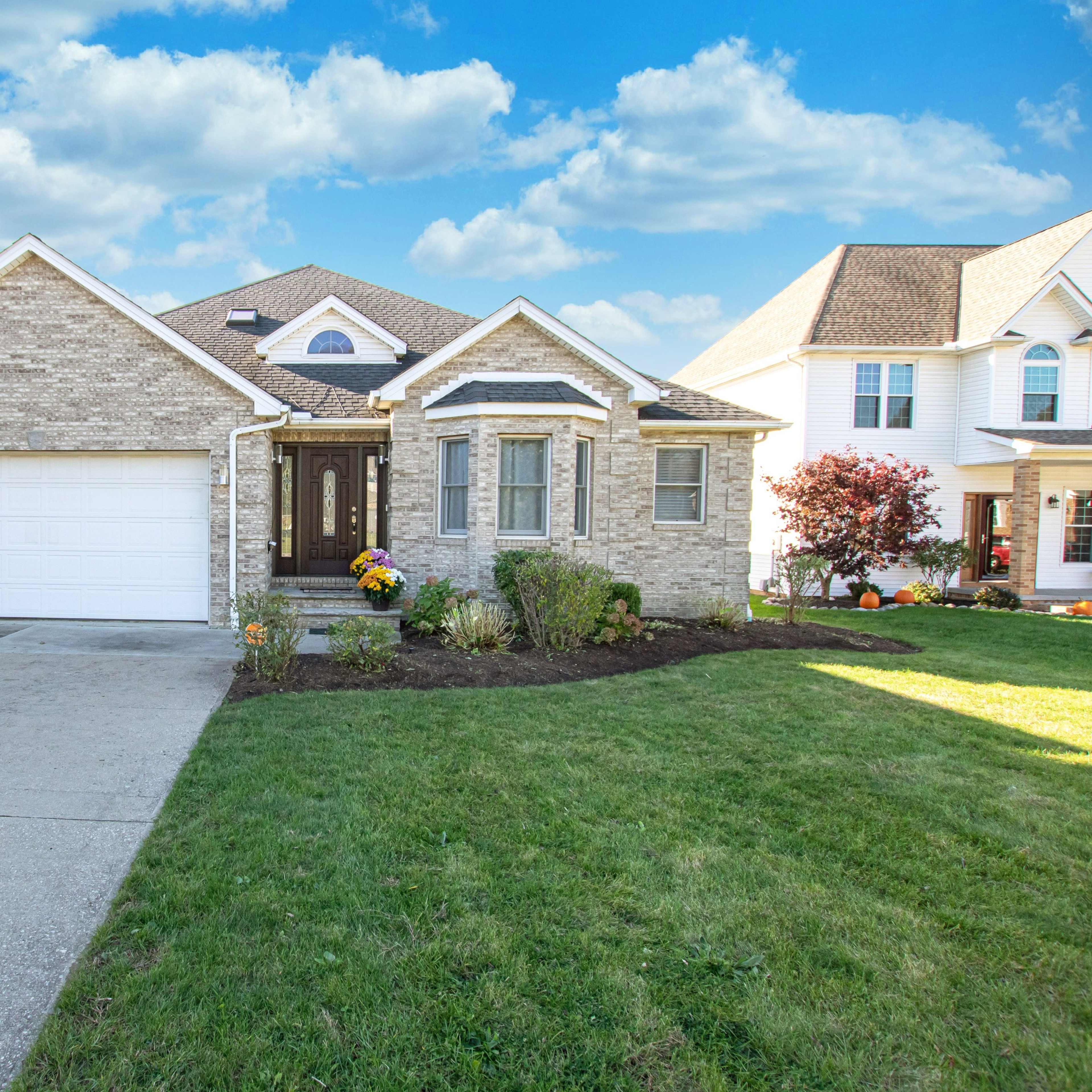 A single-story brick house with a landscaped front yard and a concrete driveway leading to a two-car garage.