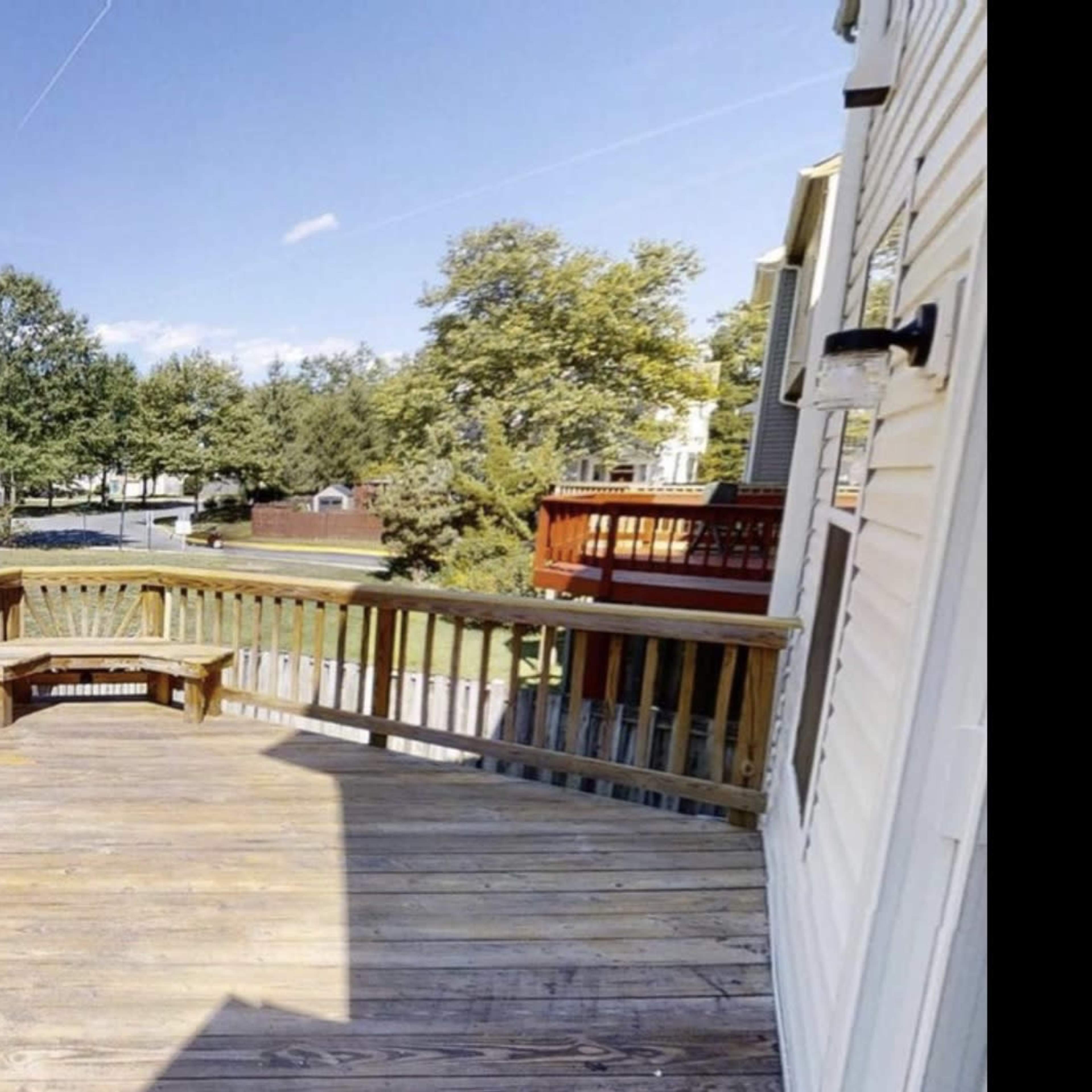 A wooden deck overlooking a grassy area with trees and nearby houses.