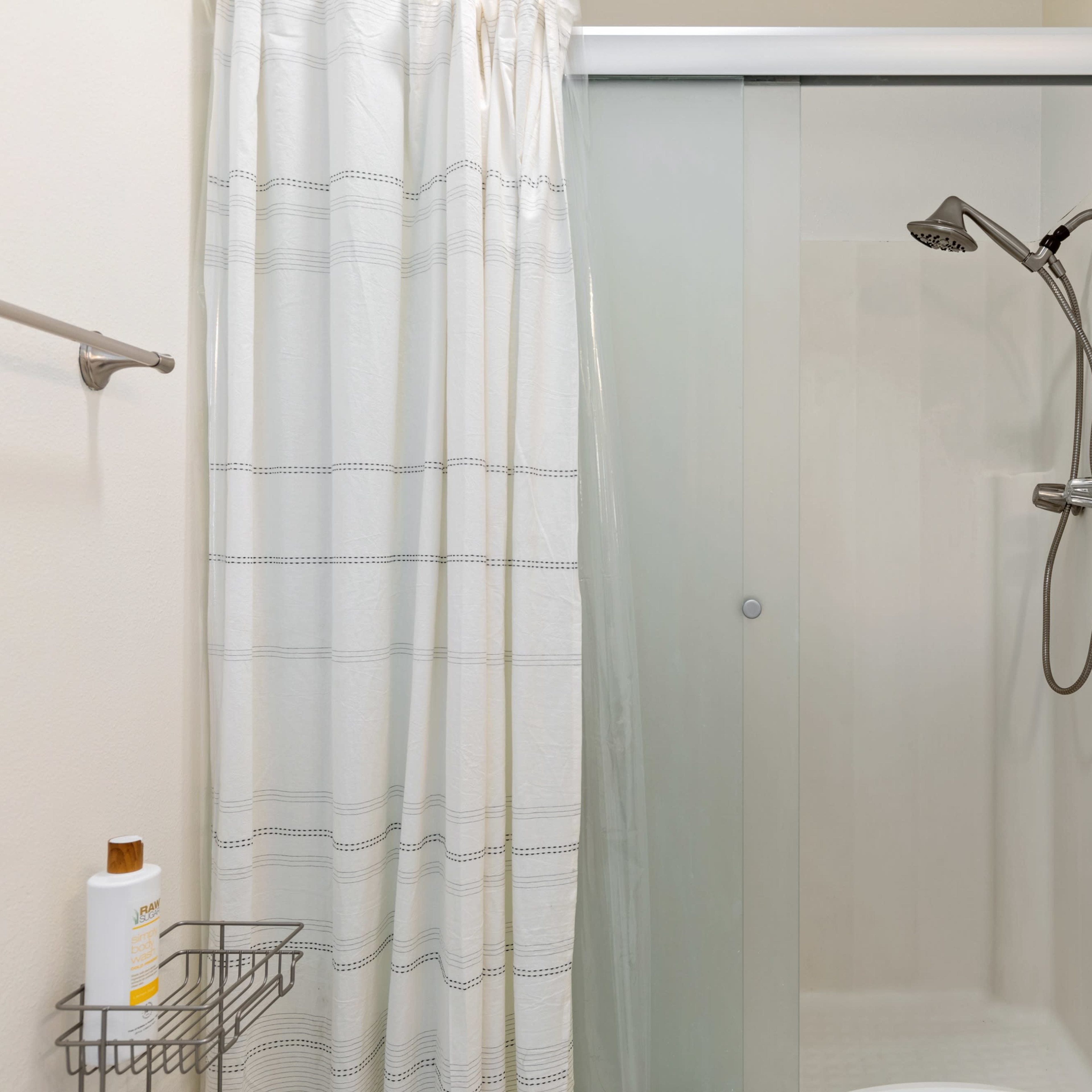 A modern bathroom with a glass shower enclosure, a toilet, and a showerhead attached to the wall.