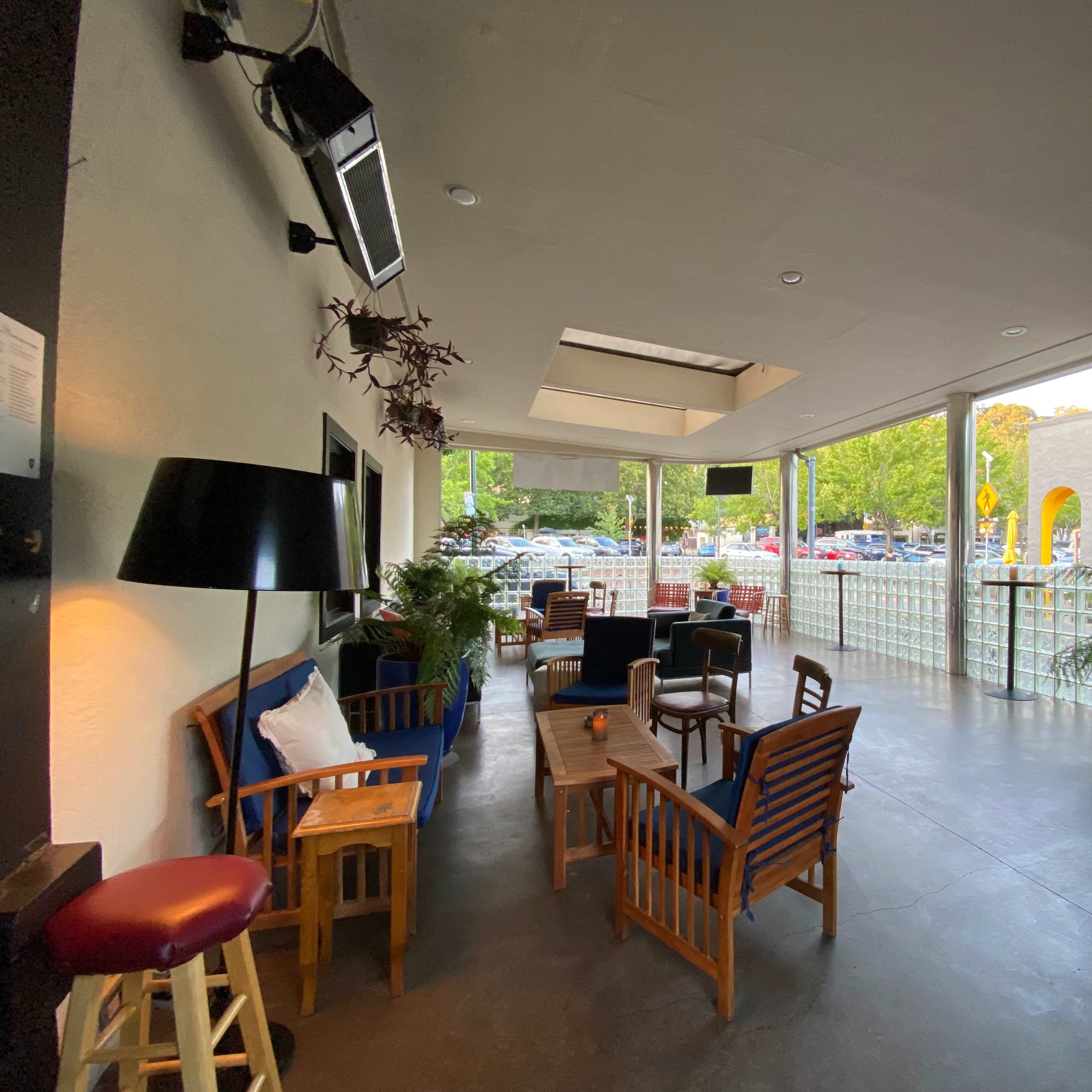 A spacious indoor area features wooden seating arrangements and large windows overlooking a parking lot.