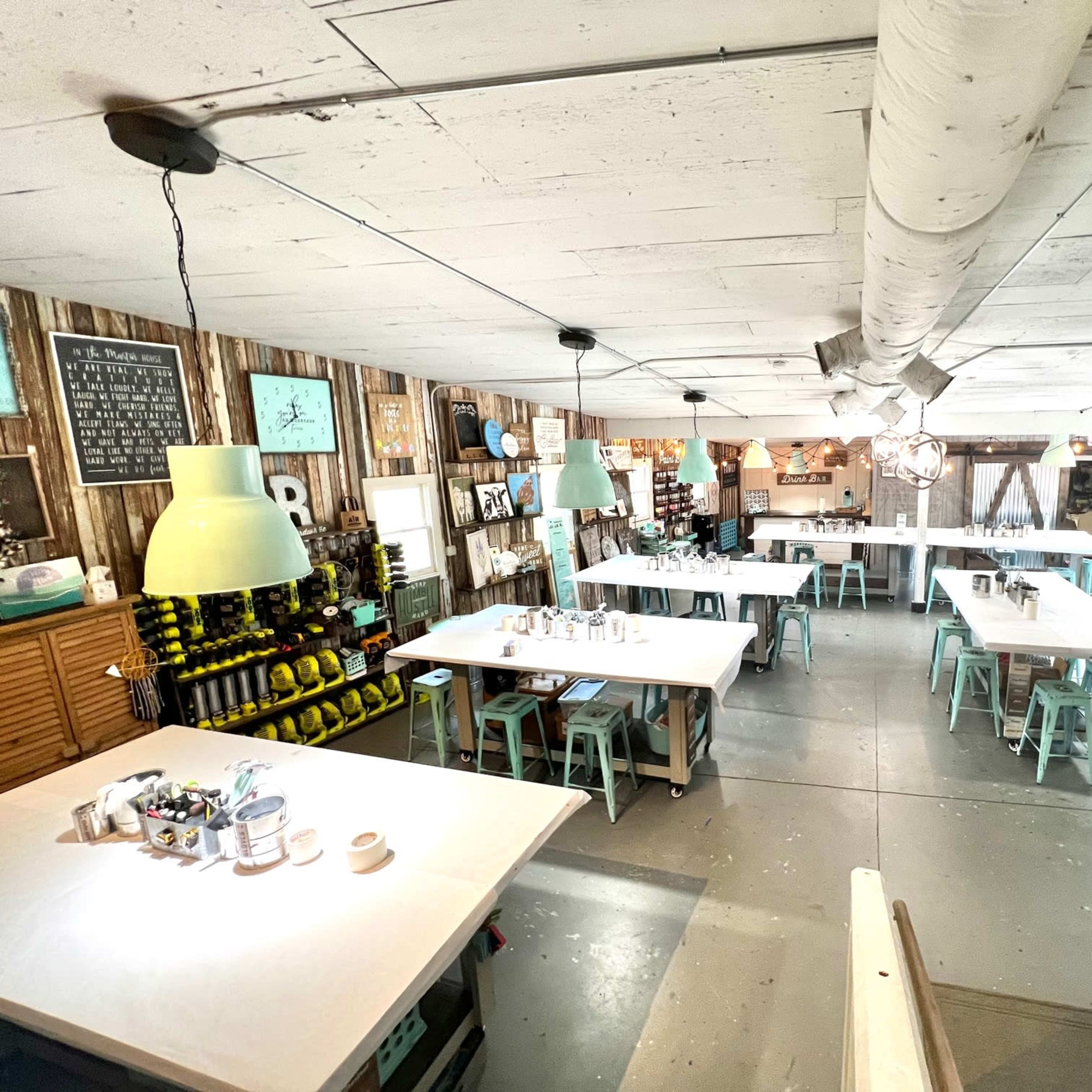 A spacious, well-lit room set up for a workshop, featuring multiple tables and stools organized in a grid pattern.