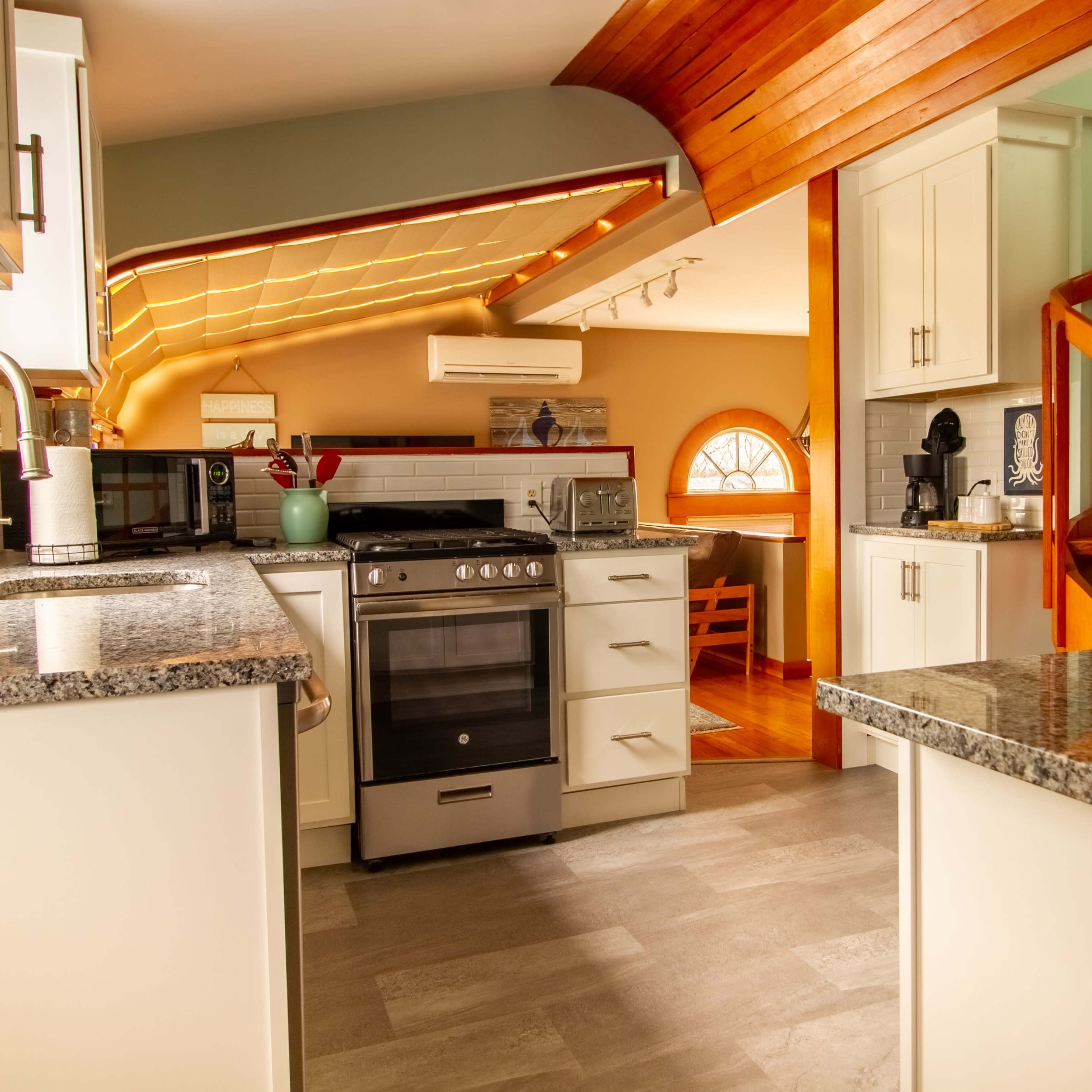 A modern kitchen with granite countertops, white cabinetry, and an open layout that leads to a wooden staircase.