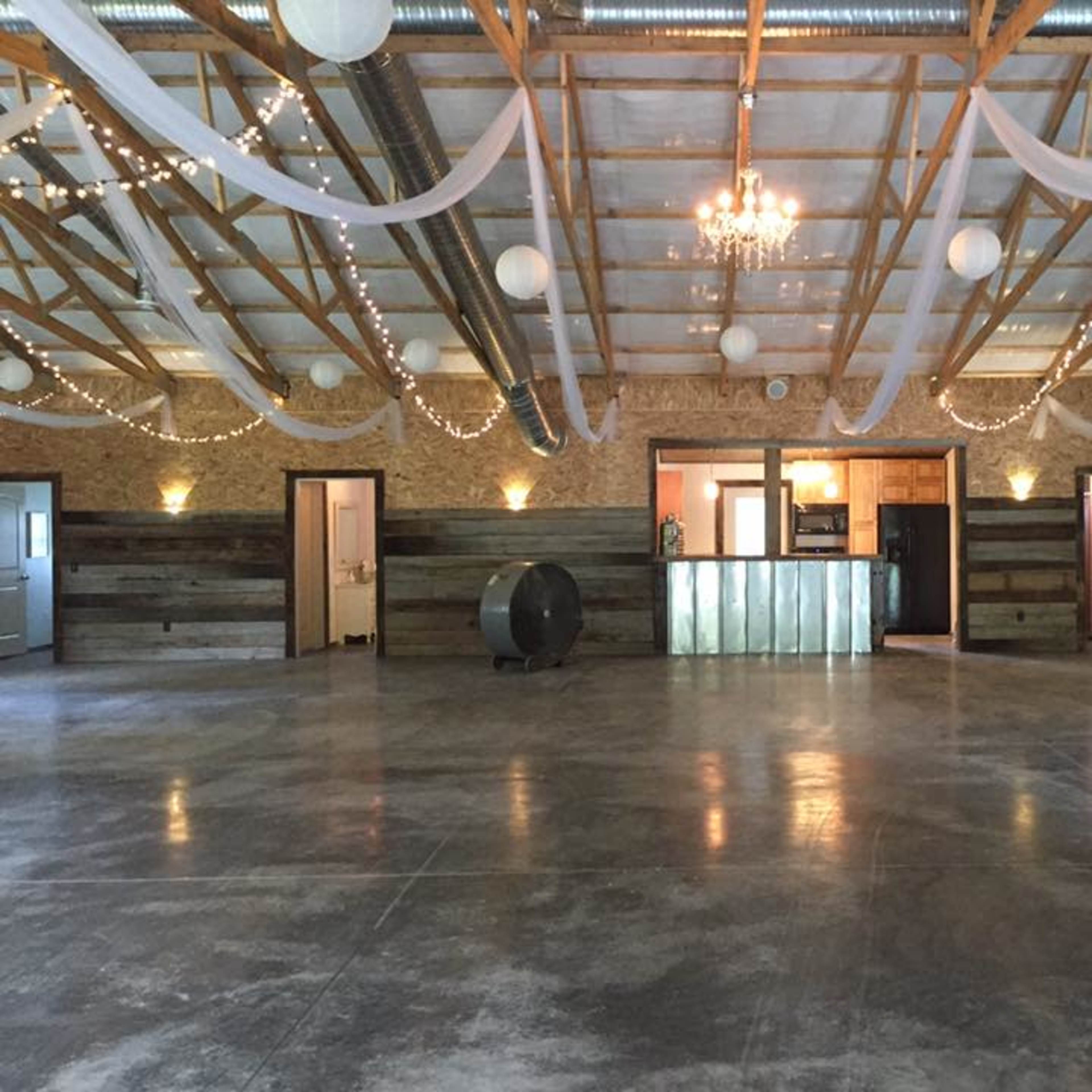 An empty indoor event space with a polished concrete floor, wooden accents on the walls, and decorative lighting.
