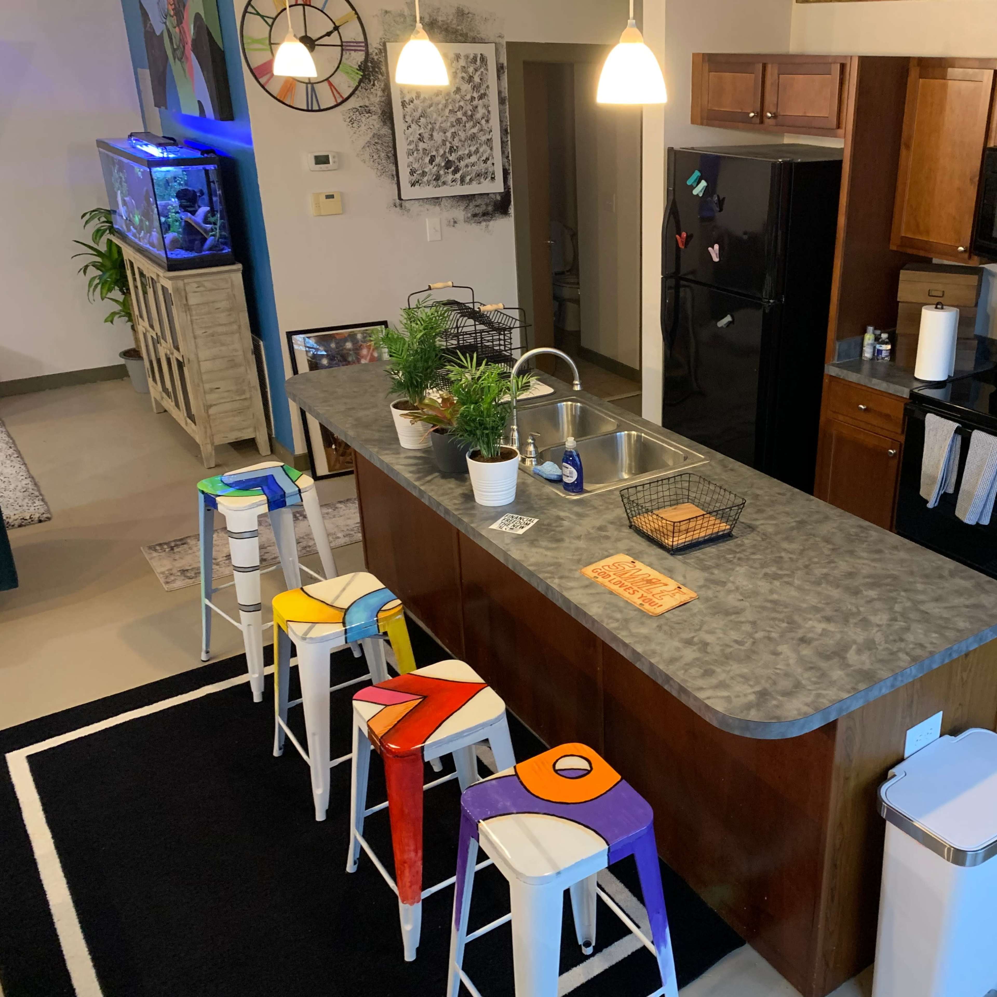 A modern kitchen with wooden cabinets, a central island equipped with bar stools, and an open layout that connects to a living area.