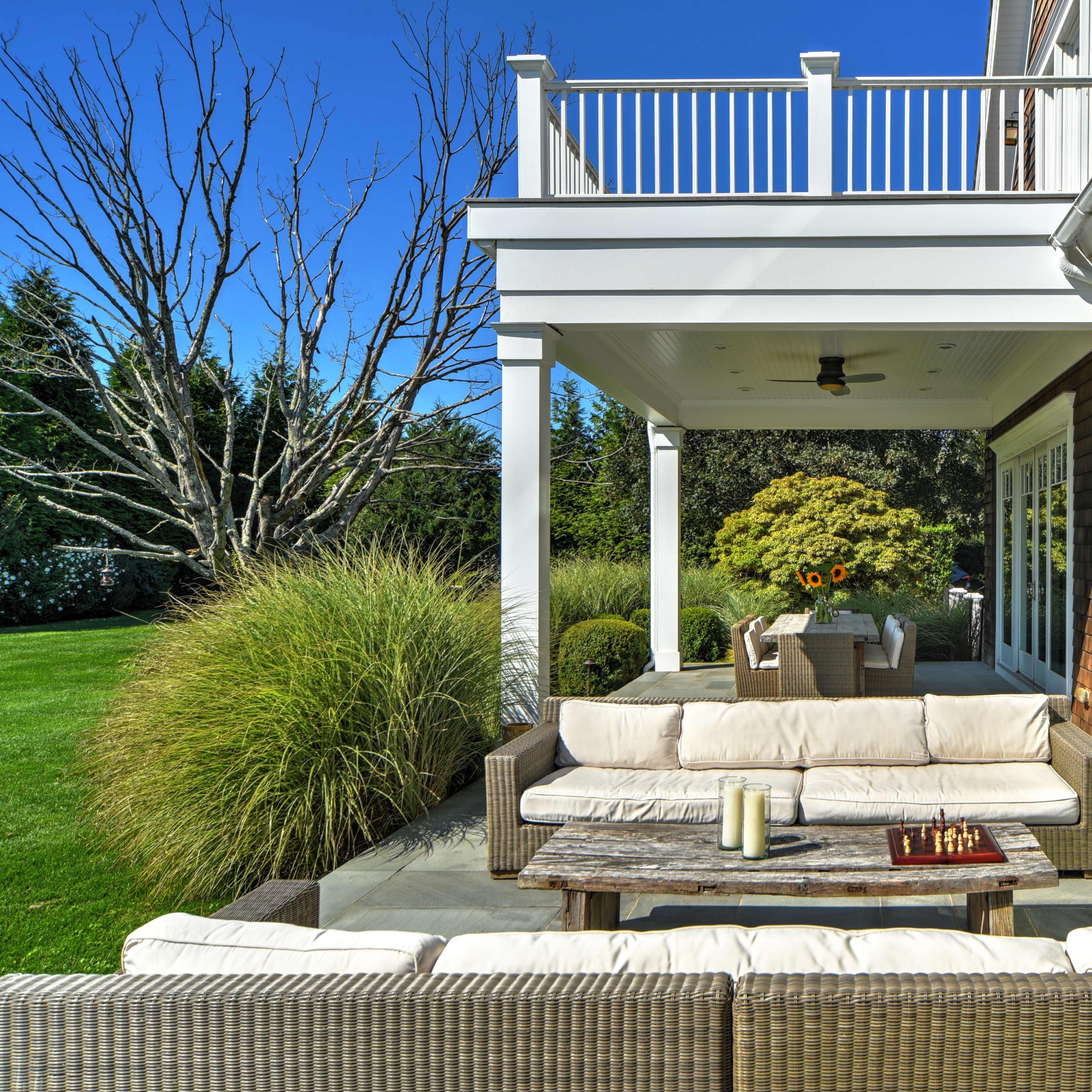 A well-furnished outdoor patio with a seating area, a coffee table, and a dining table visible in the background.