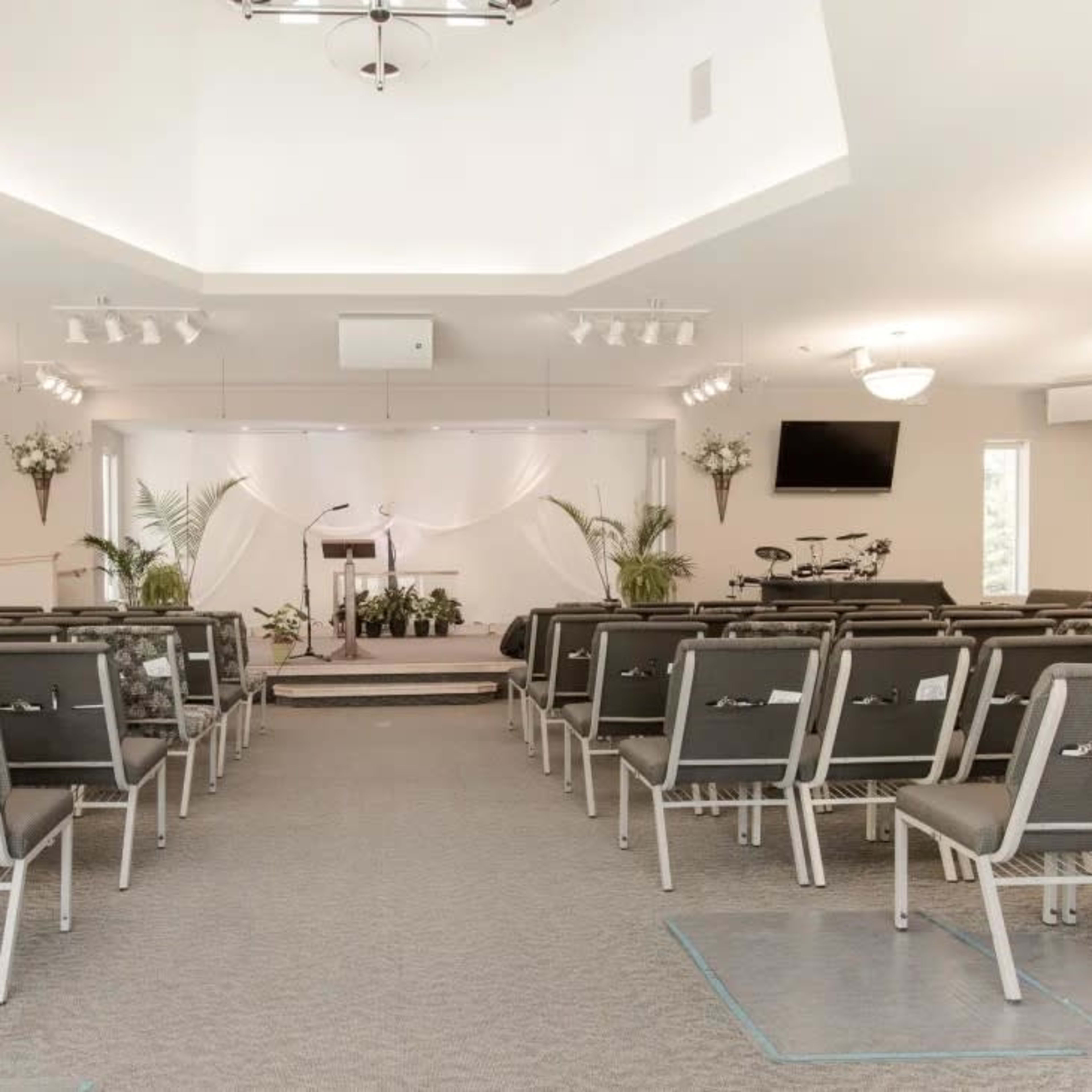 A spacious, empty church auditorium with rows of chairs facing a stage that has a podium and musical instruments.