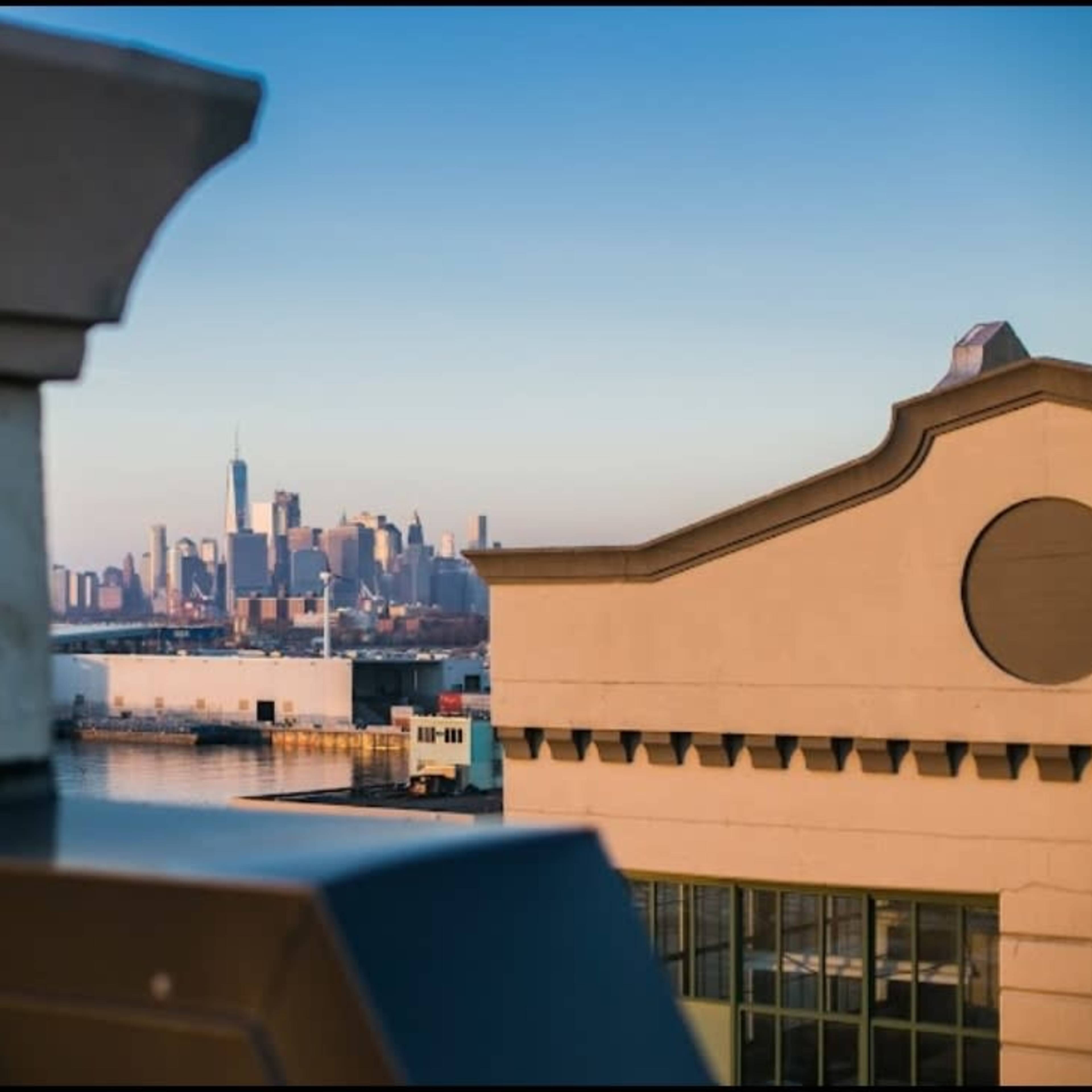 A view of a city skyline, partially obscured by building architecture in the foreground.
