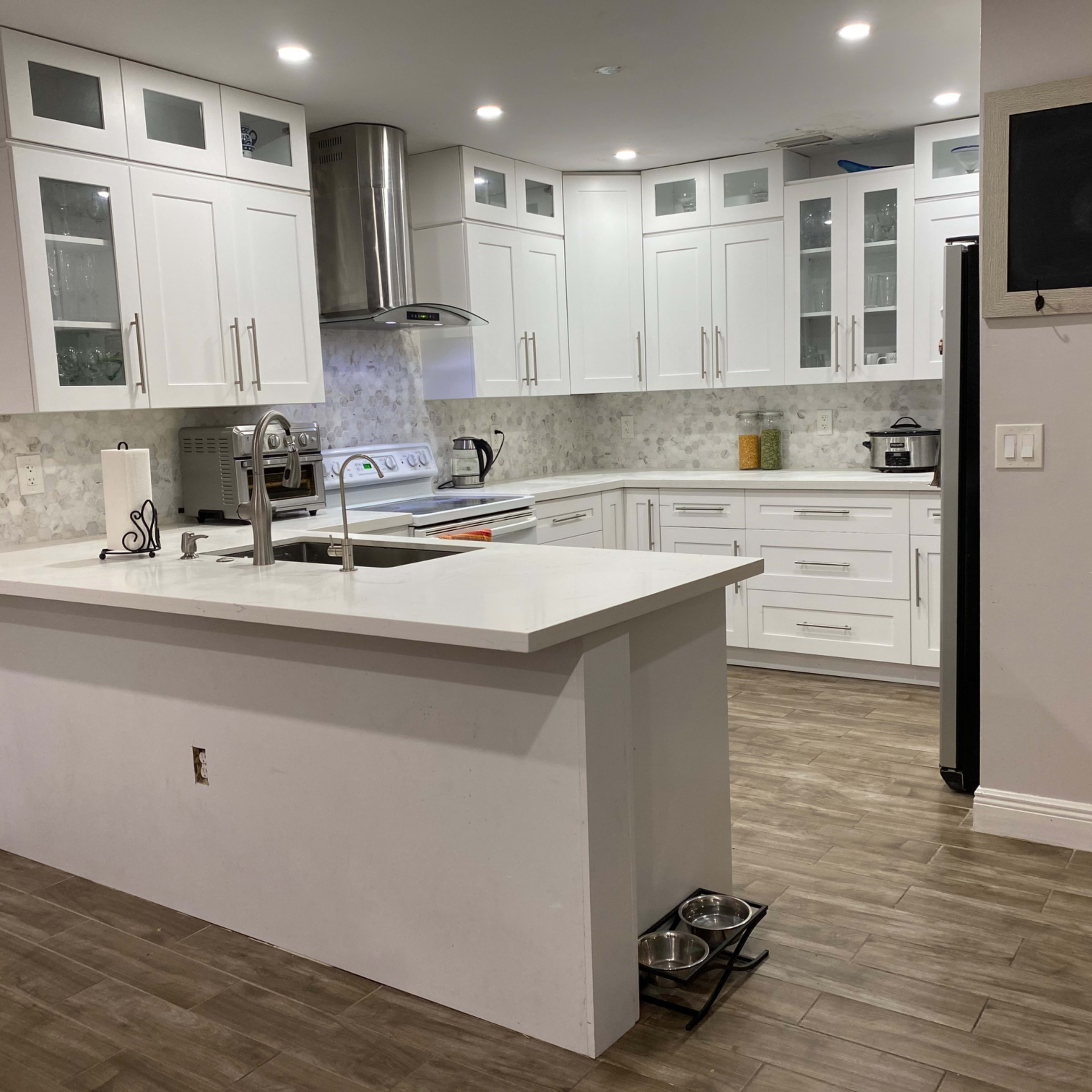 A modern kitchen with white cabinetry, a central island, and tile flooring.