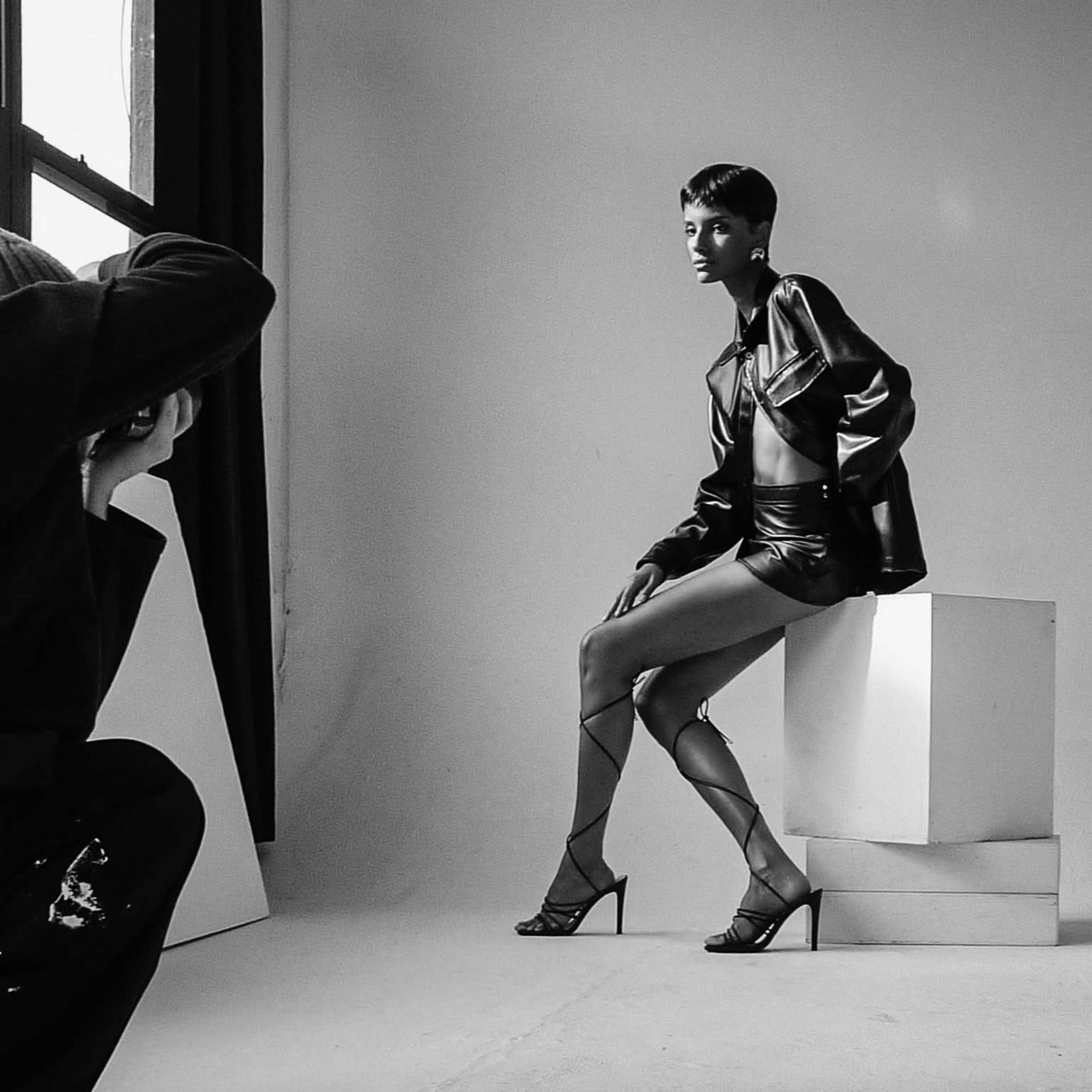 A photographer captures a model posing in high fashion attire in a studio setting.