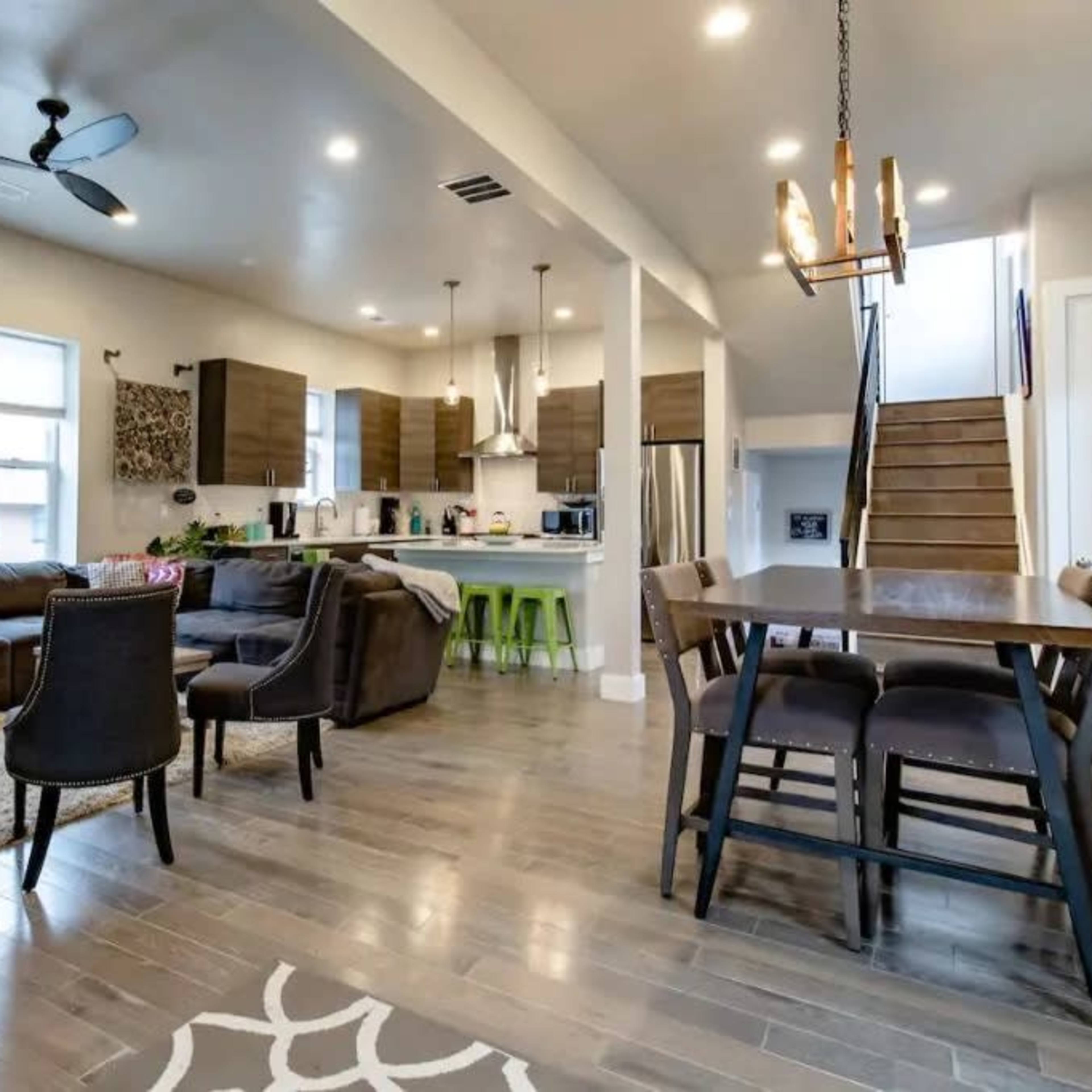 A modern open-concept living and dining area with a sofa, dining table, and kitchen in a well-lit space.