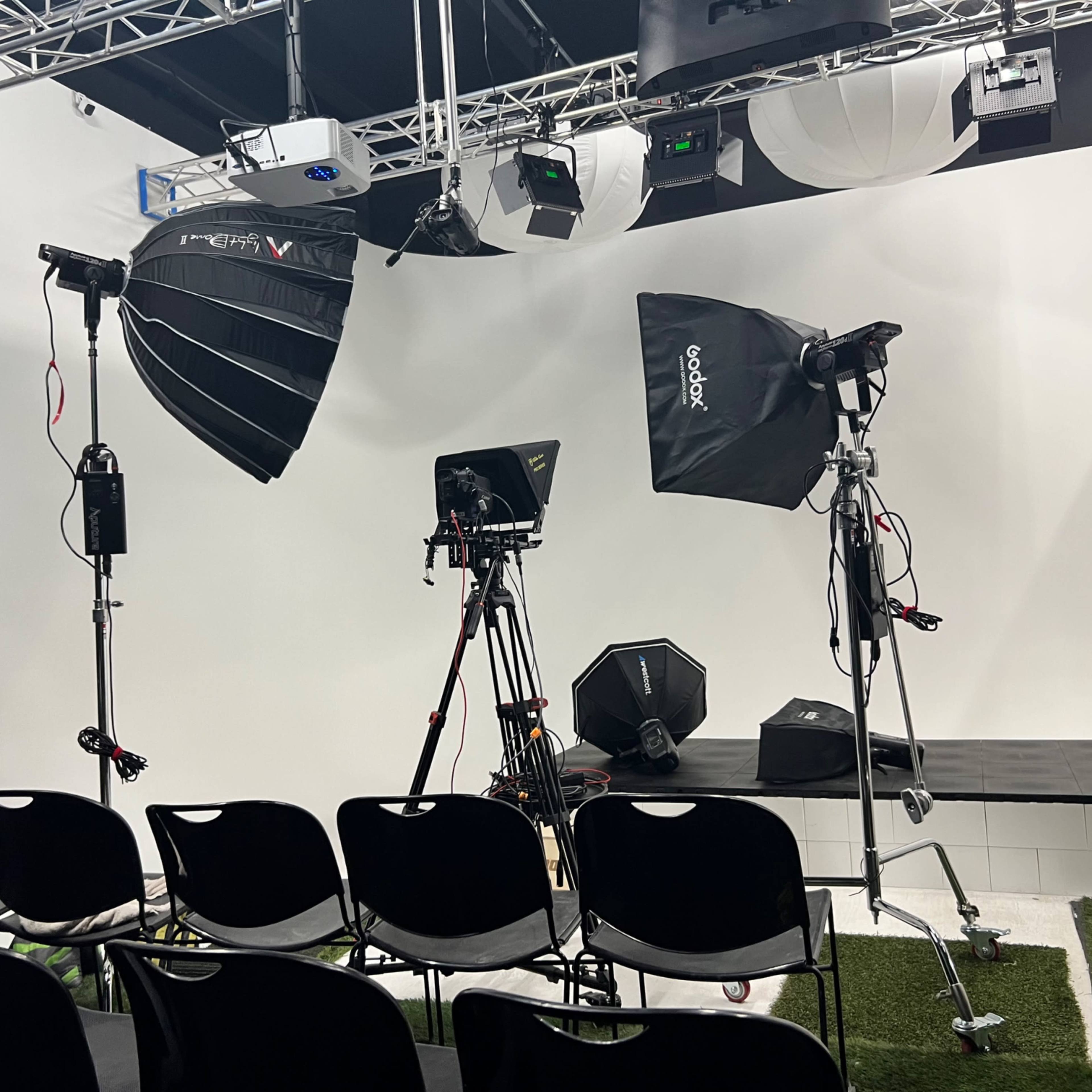 A photography studio setup with various lighting equipment, tripods, and a backdrop.