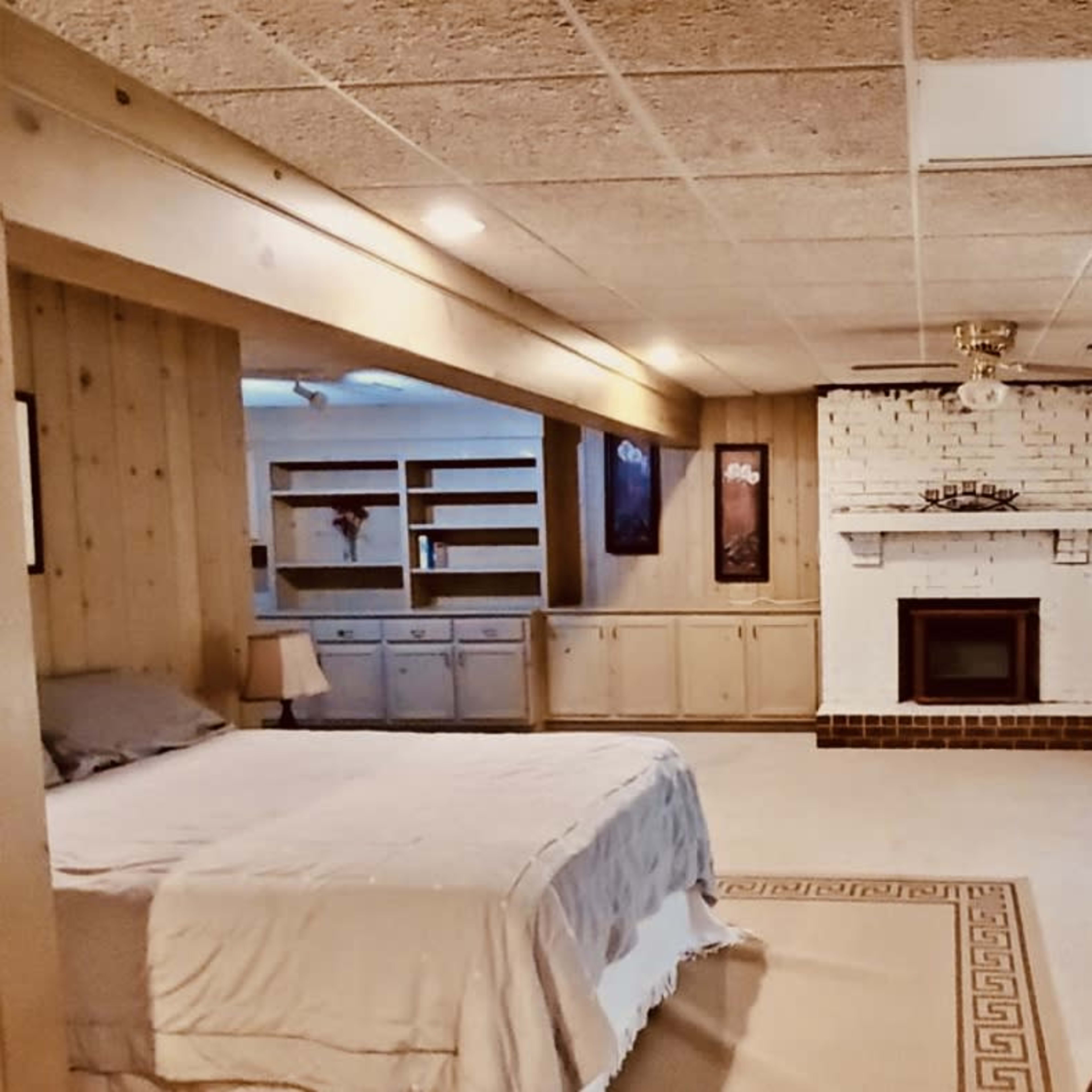 A spacious, well-lit room with a bed, a fireplace, and sliding glass doors leading to an outdoor area.