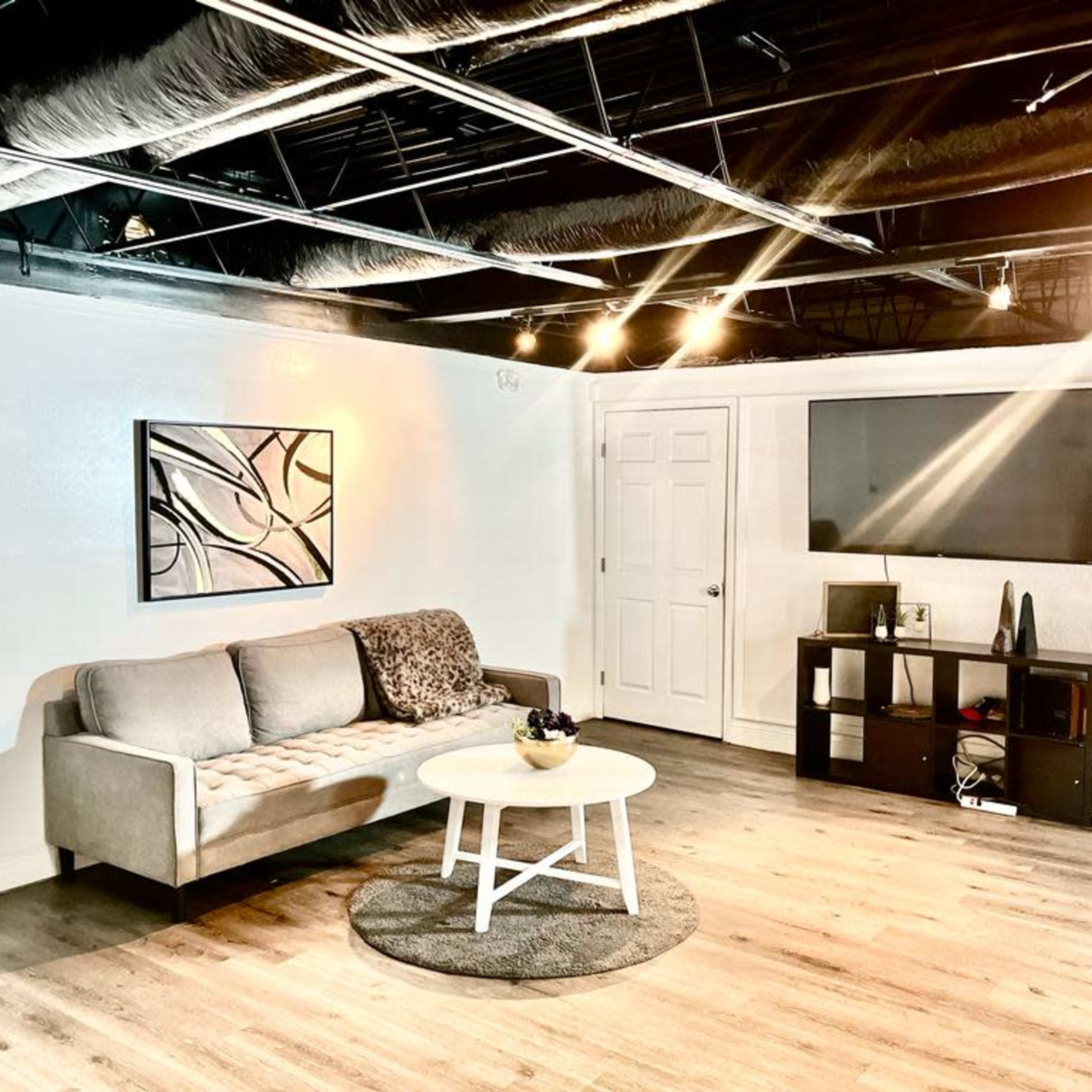 A modern, minimalistic living space with a gray sofa, a round coffee table, and a television mounted on the wall.